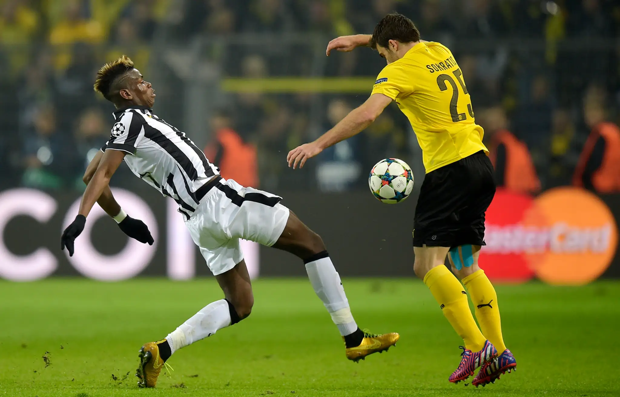 Hráč Juventusu Paul Pogba a vpravo hráč Dortmundu Sokratis Papastathopoulos v semifinále Ligy majstrov Borussia Dortmund - Juven