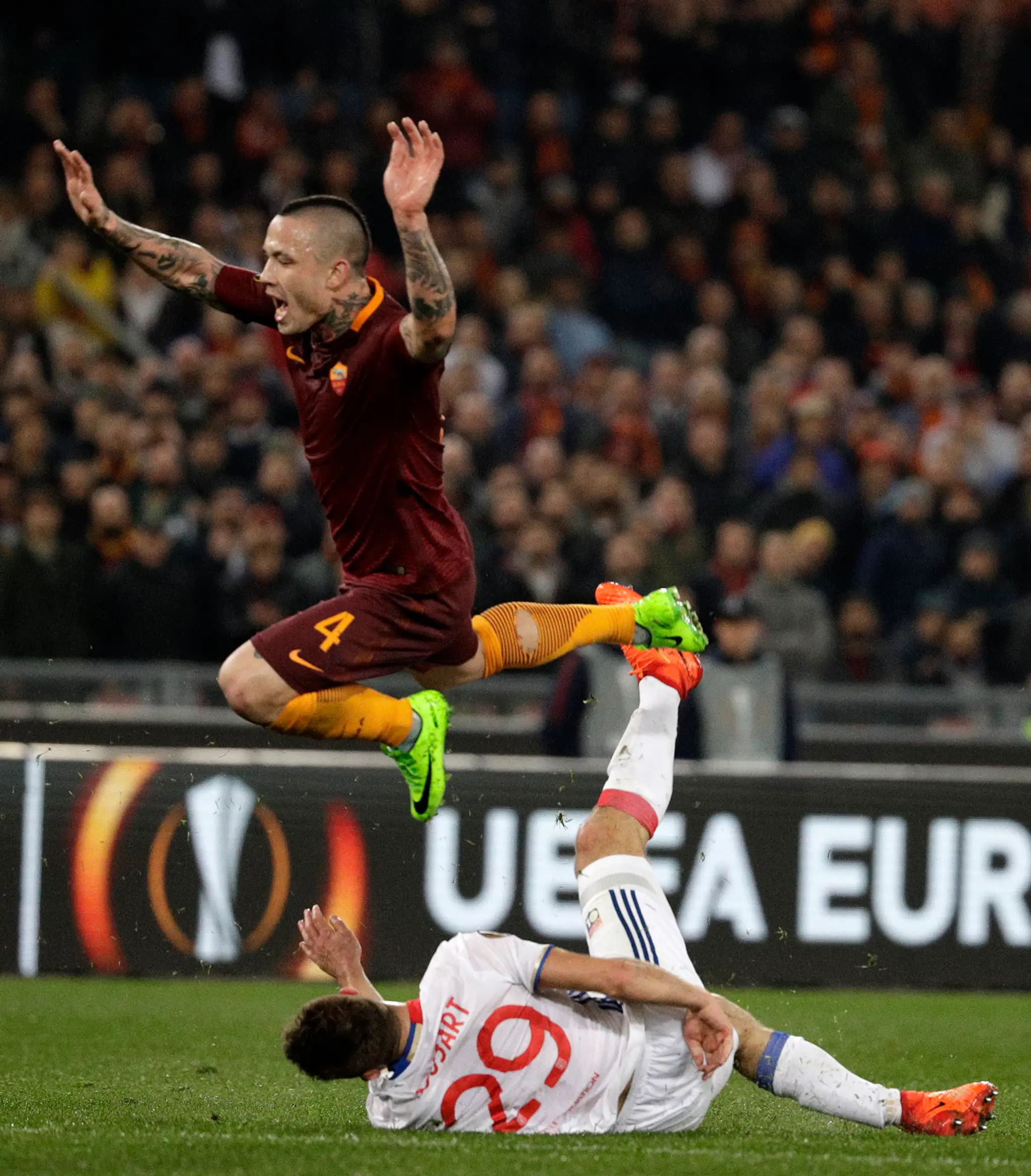 Radja Nainggolan (vo výskoku) z AS Rím pociťuje zákrok Lucasa Tousarta z Lyonu v odvete osemfinále EL.
