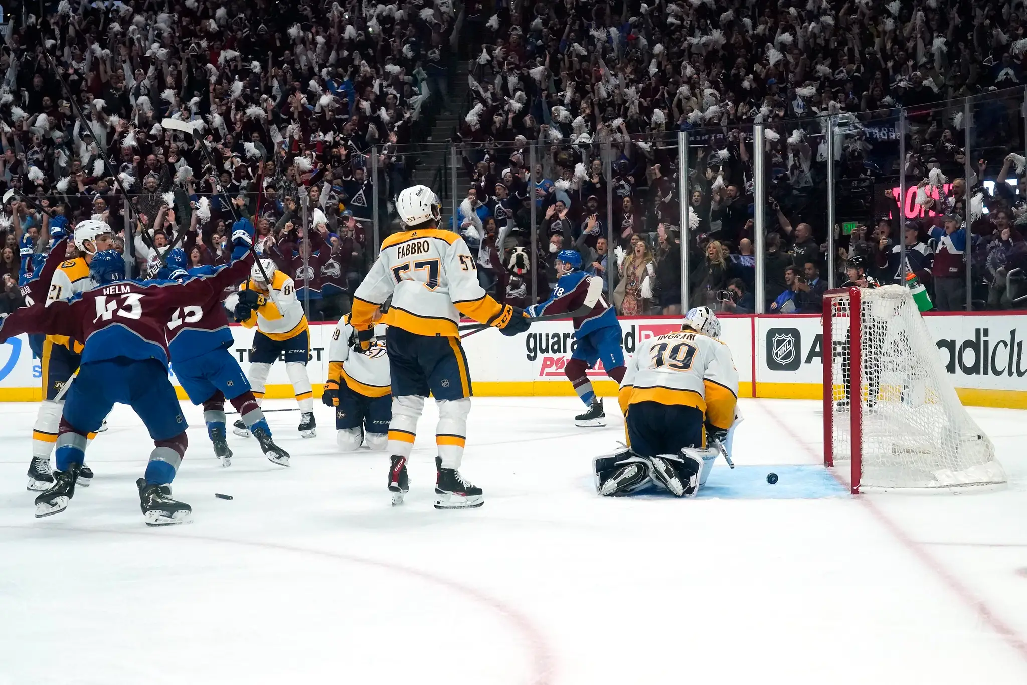Hokejista Colorada Avalanche Cale Makar (v pozadí vľavo) sa teší po strelení víťazného gólu za chrbát brankára Nashville Predators Connora Ingrama.