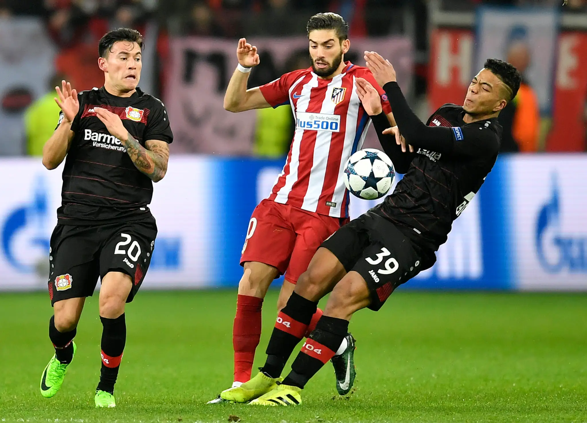 Yannick Carrasco (v strede) z Atlética v obklopení dvojice Leverkusenu Charles Aranguiz (vľavo) a Benjamin Henrichs v osemfinále