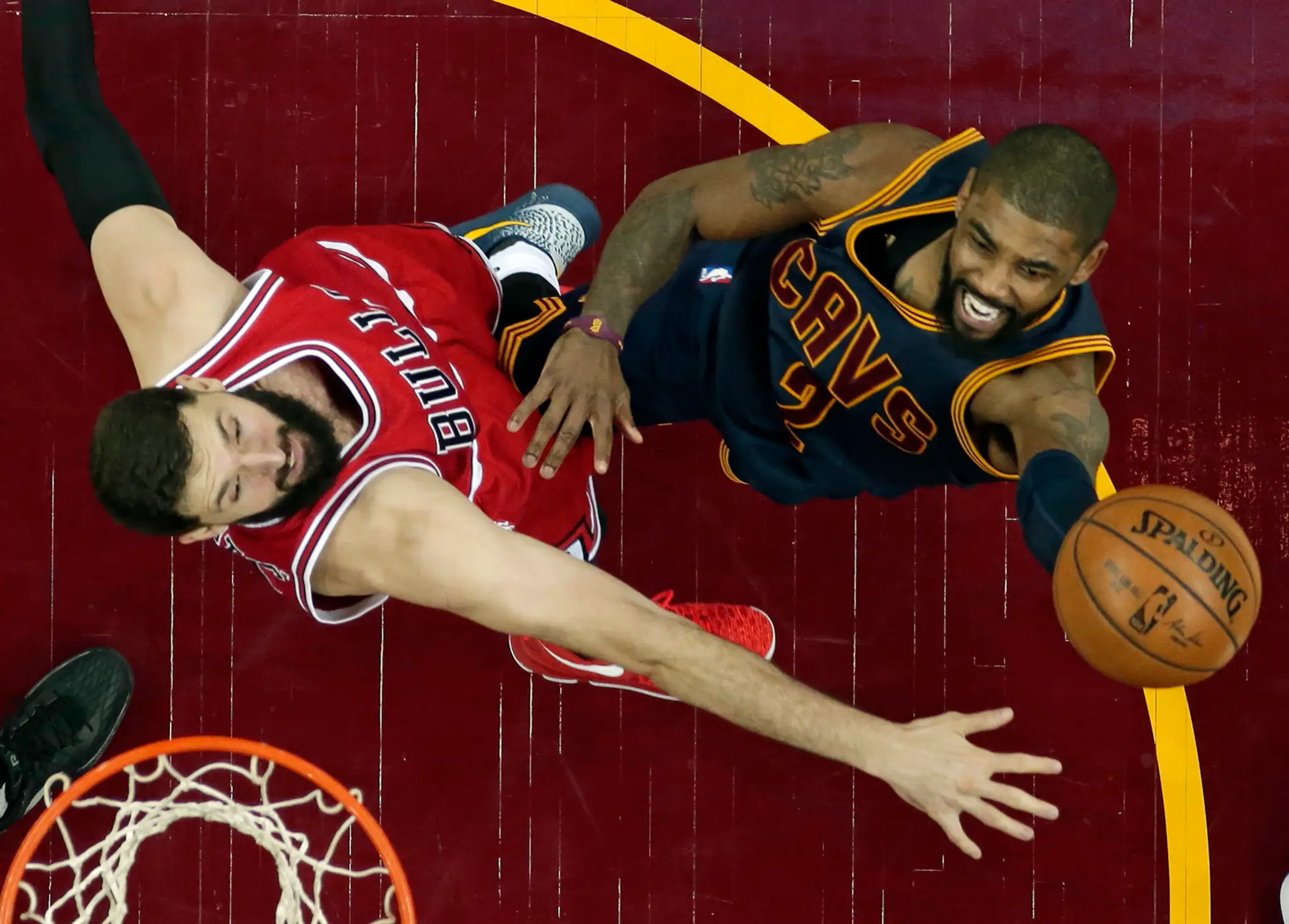 Na snímke vpravo hráč Cavaliers Kyrie Irving strieľa na kôš cez hráča Bulls Nikolu Mirotiča.