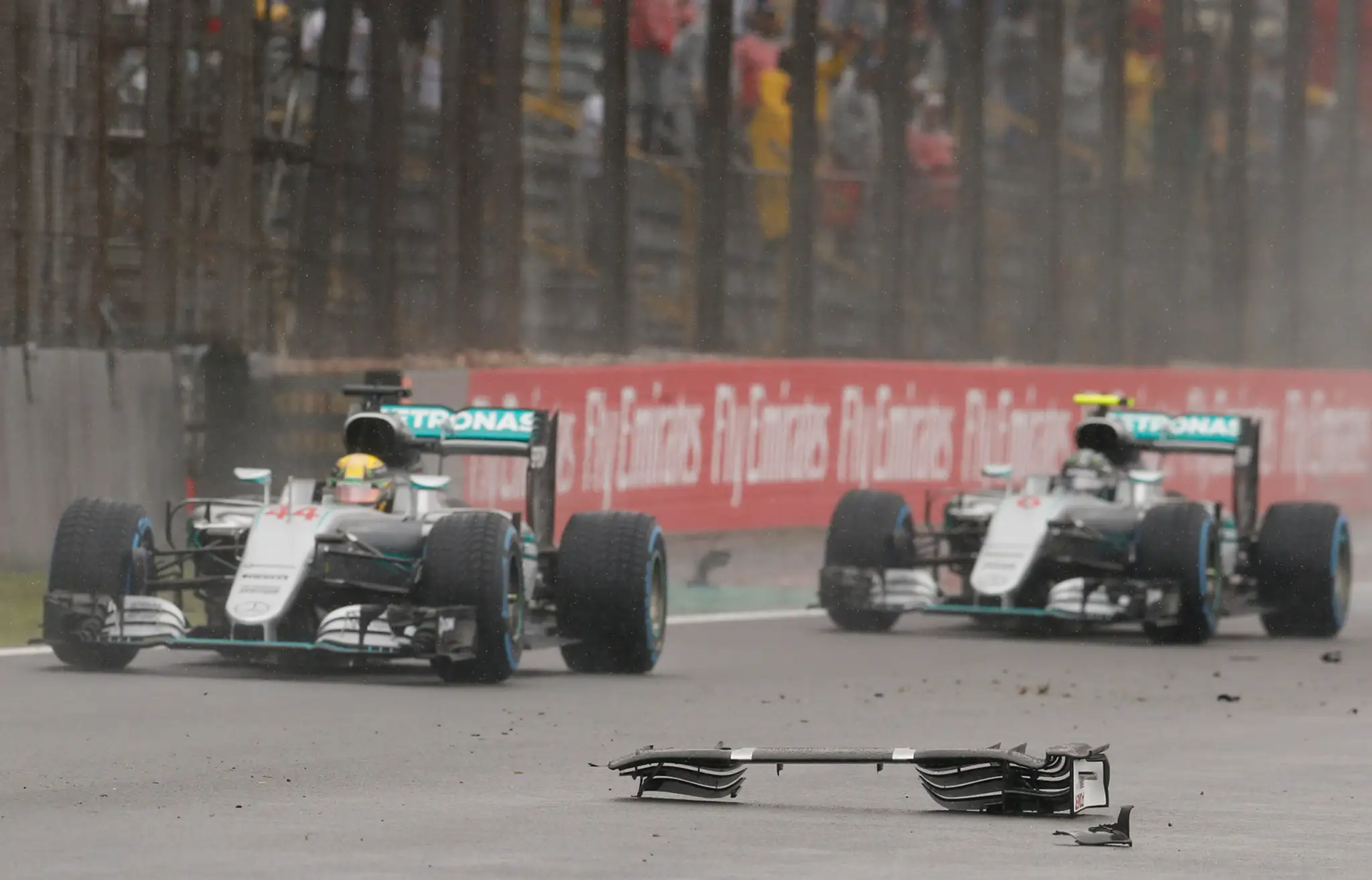 Lewis Hamilton a Nico Rosberg obchádzajú trosky monopostu Kimiho Räikkönnena, ktorý pre aquaplaning havaroval.