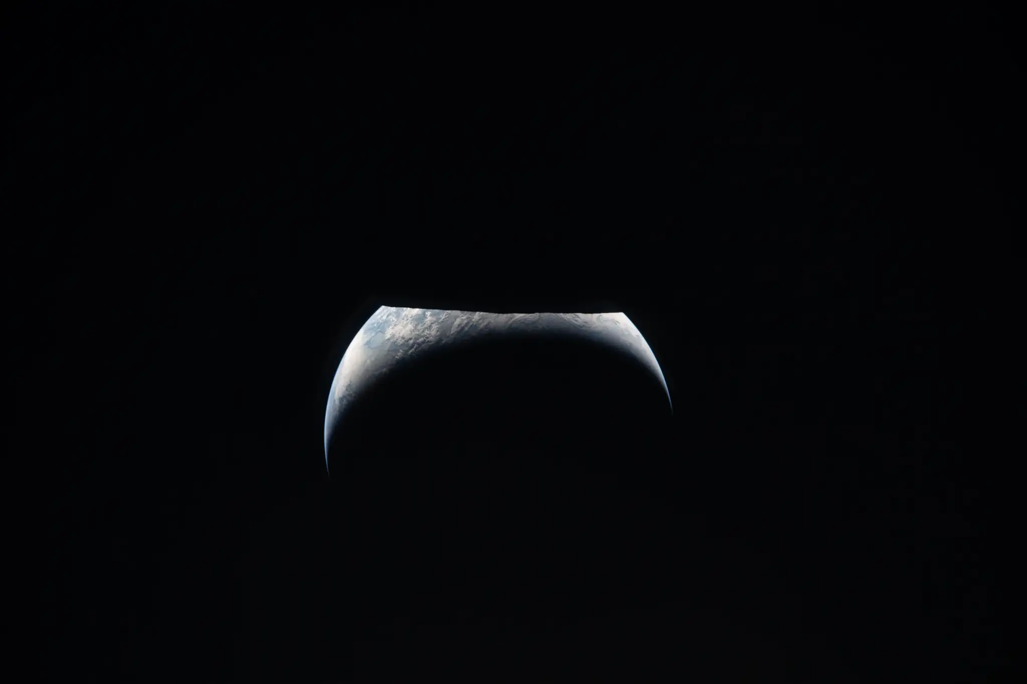 Na tomto obrázku, ktorý poskytla NASA, posádka Artemis II zachytila ​​pohľad na Zem, ktorá sa počas preletu okolo Mesiaca vynára spoza Mesiaca.