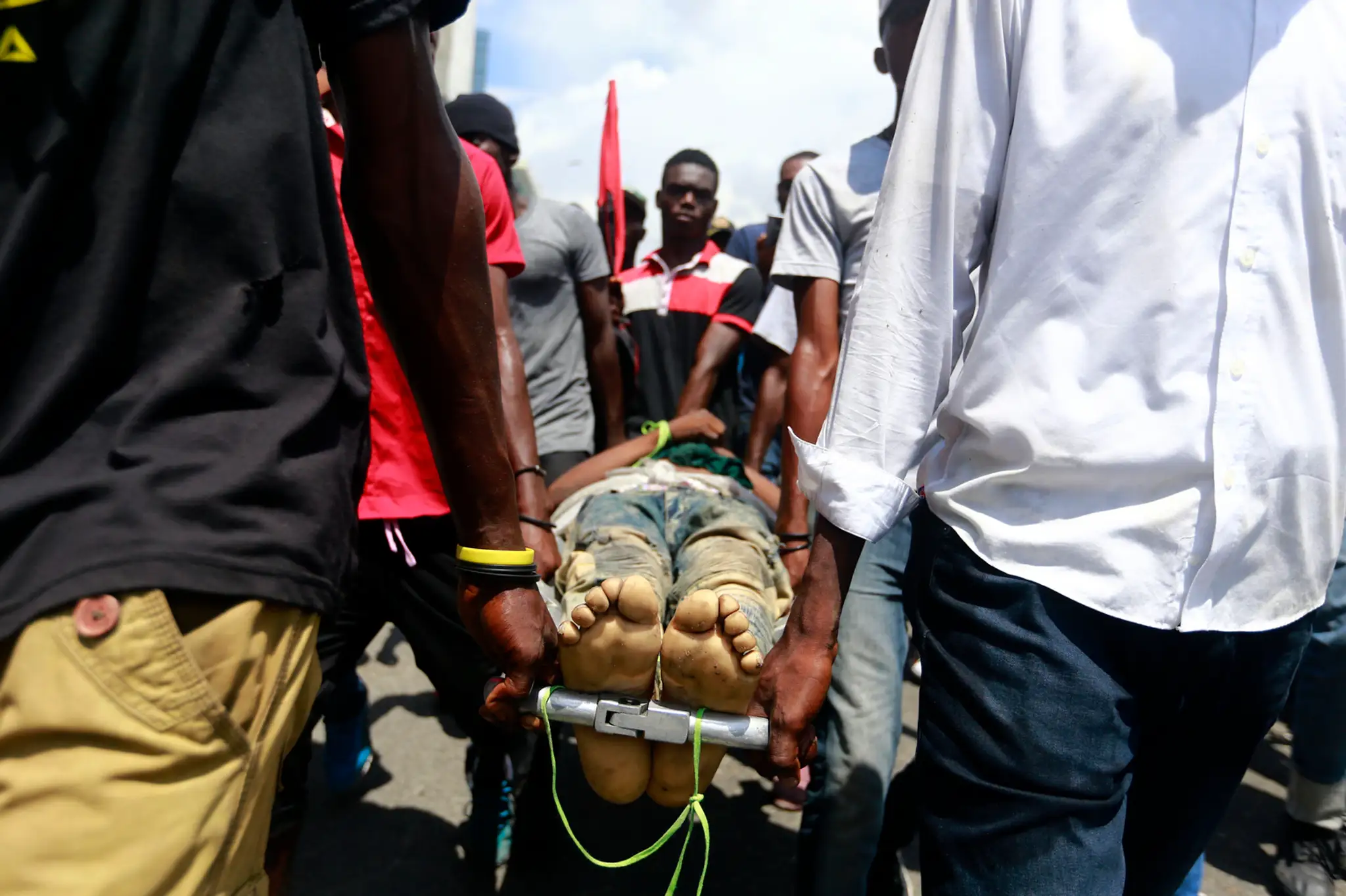 Vojak odťahuje horiacu pneumatiku počas protestov na Haiti.