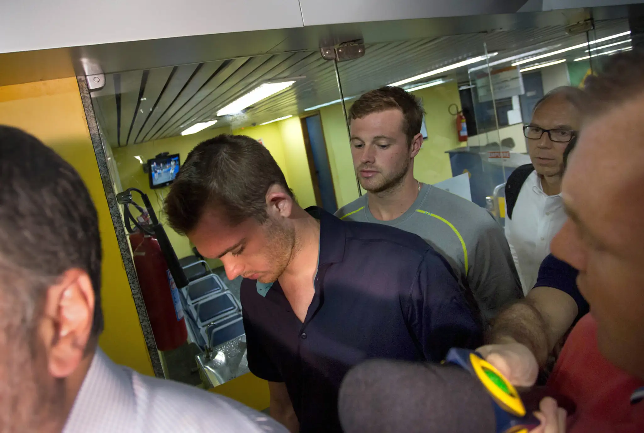 Americkí plavci Gunnar Bentz a Jack Conger odchádzajú z policajnej stanice na medzinárodnom letisku v Riu de Janeiro.