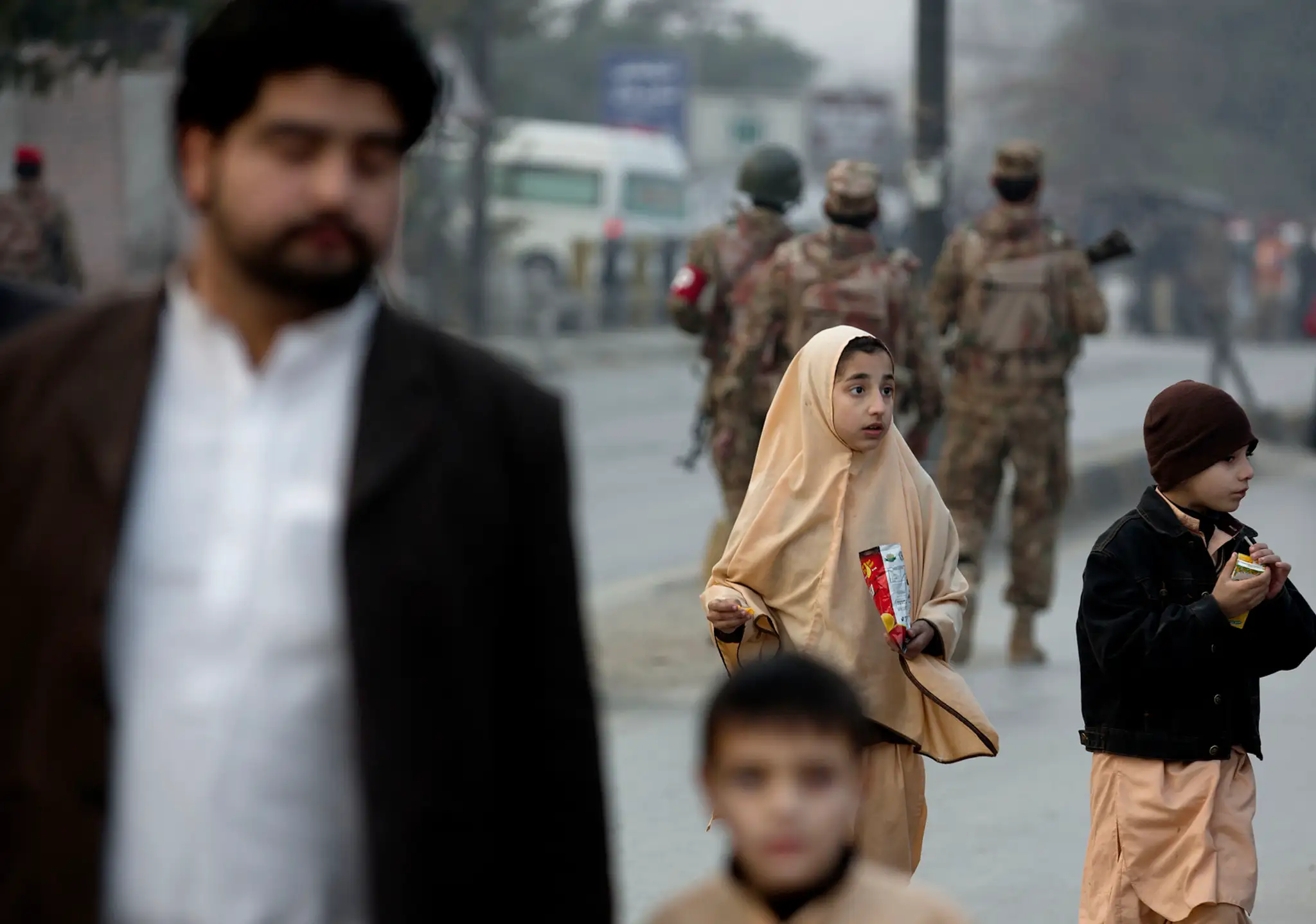 Rodinný príslušník odvádza deti mimo školy, na ktorú v pakistanskom Pešaváre zaútočil Taliban. 16. decembra 