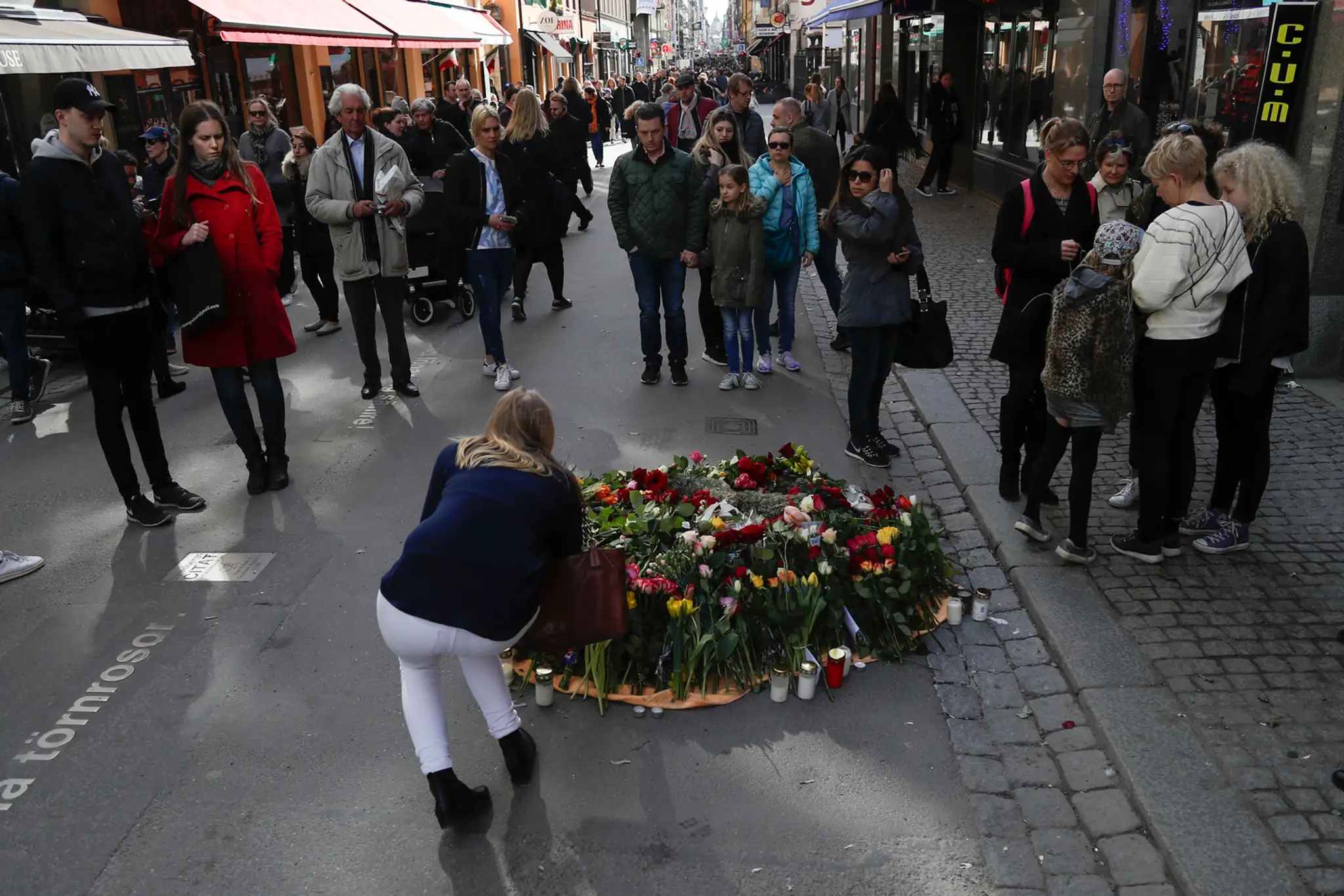 Žena kladie kvety na rušnej pešej zóne Drottninggatan v centre Štokholmu