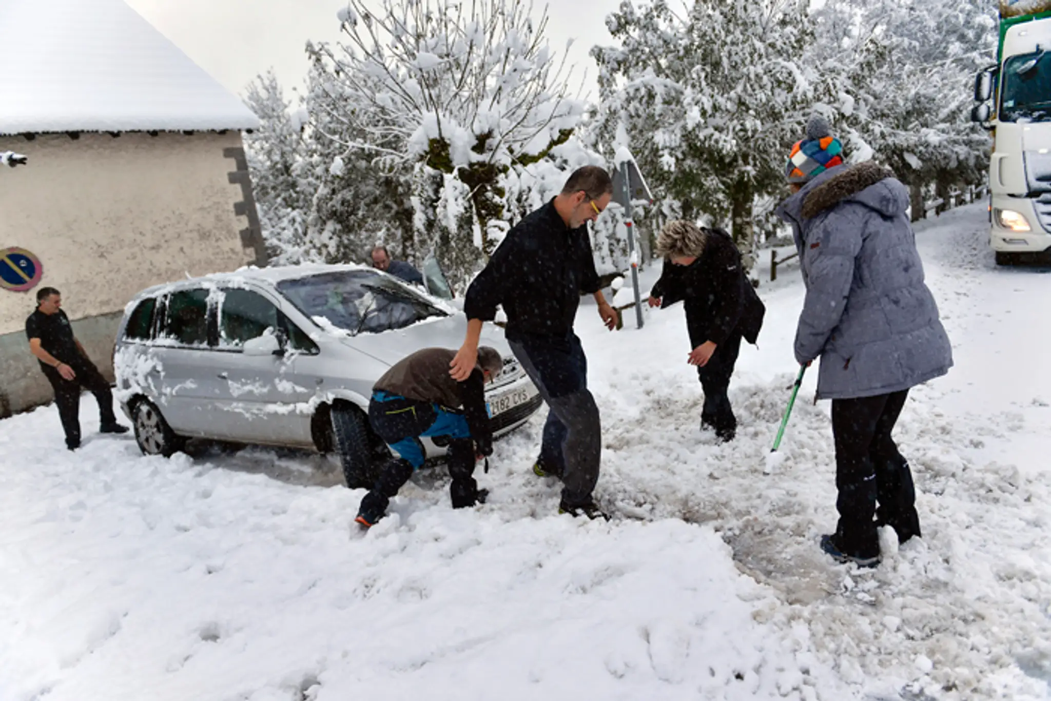 Ľudia pomáhajú odhrabať auto po silnom snežení v severošpanielskom Roncesvallese.