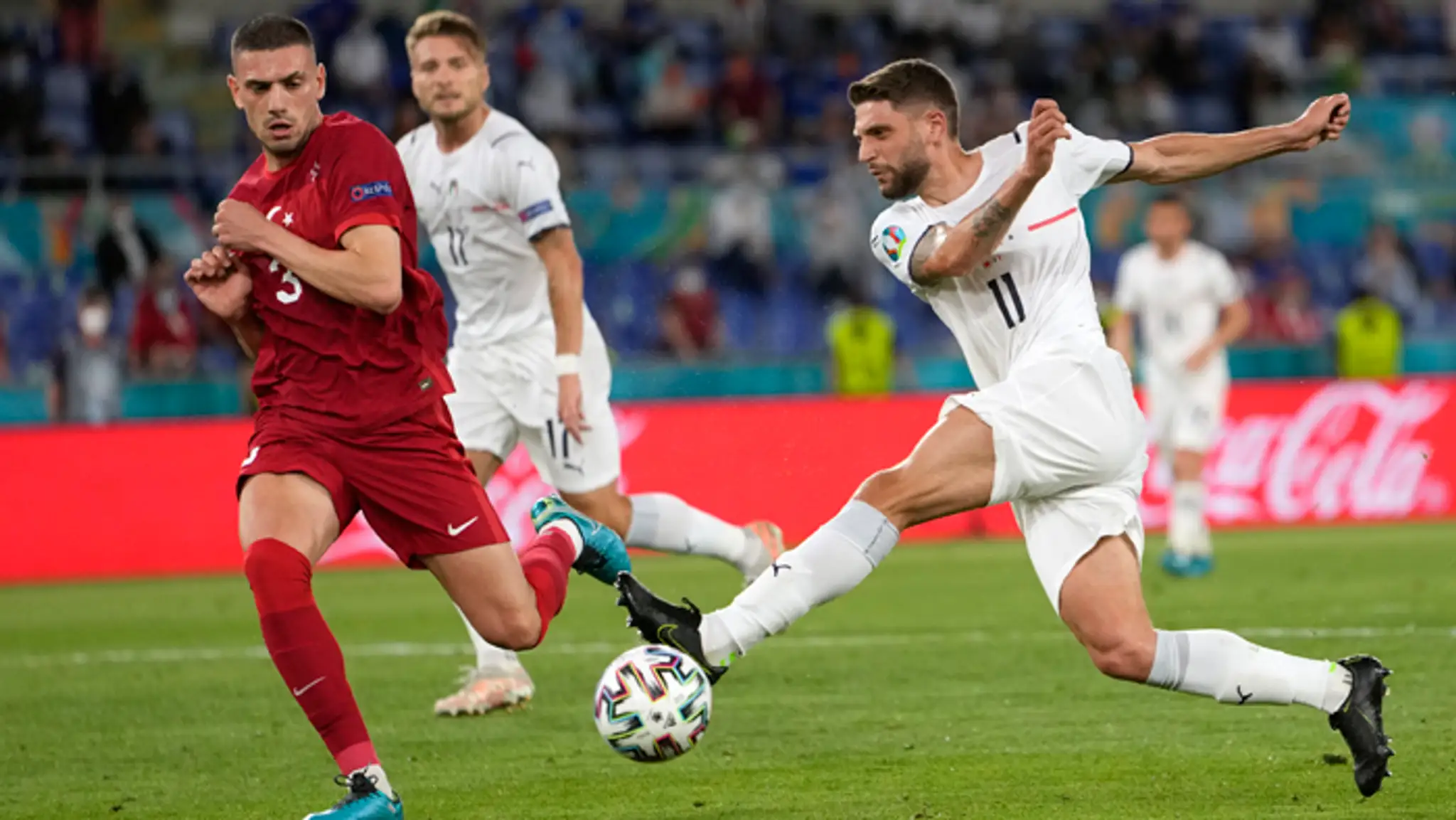 Taliansky hráč Domenico Berardi (vpravo) kope do lopty cez tureckého hráča Meriha Demirala.