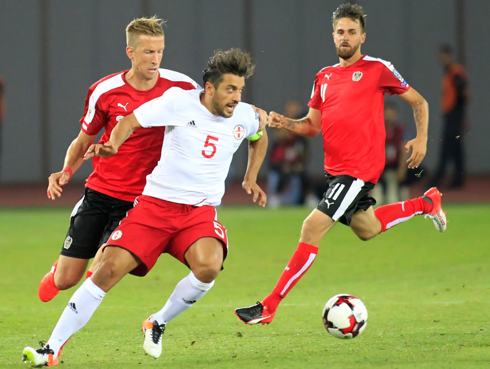 Gruzínčan Aleksandre Amisulašvili v obklopení Rakúšanov Marca Janka (vľavo) a Martina Harnika v dueli kvalifikácie MS 2018.