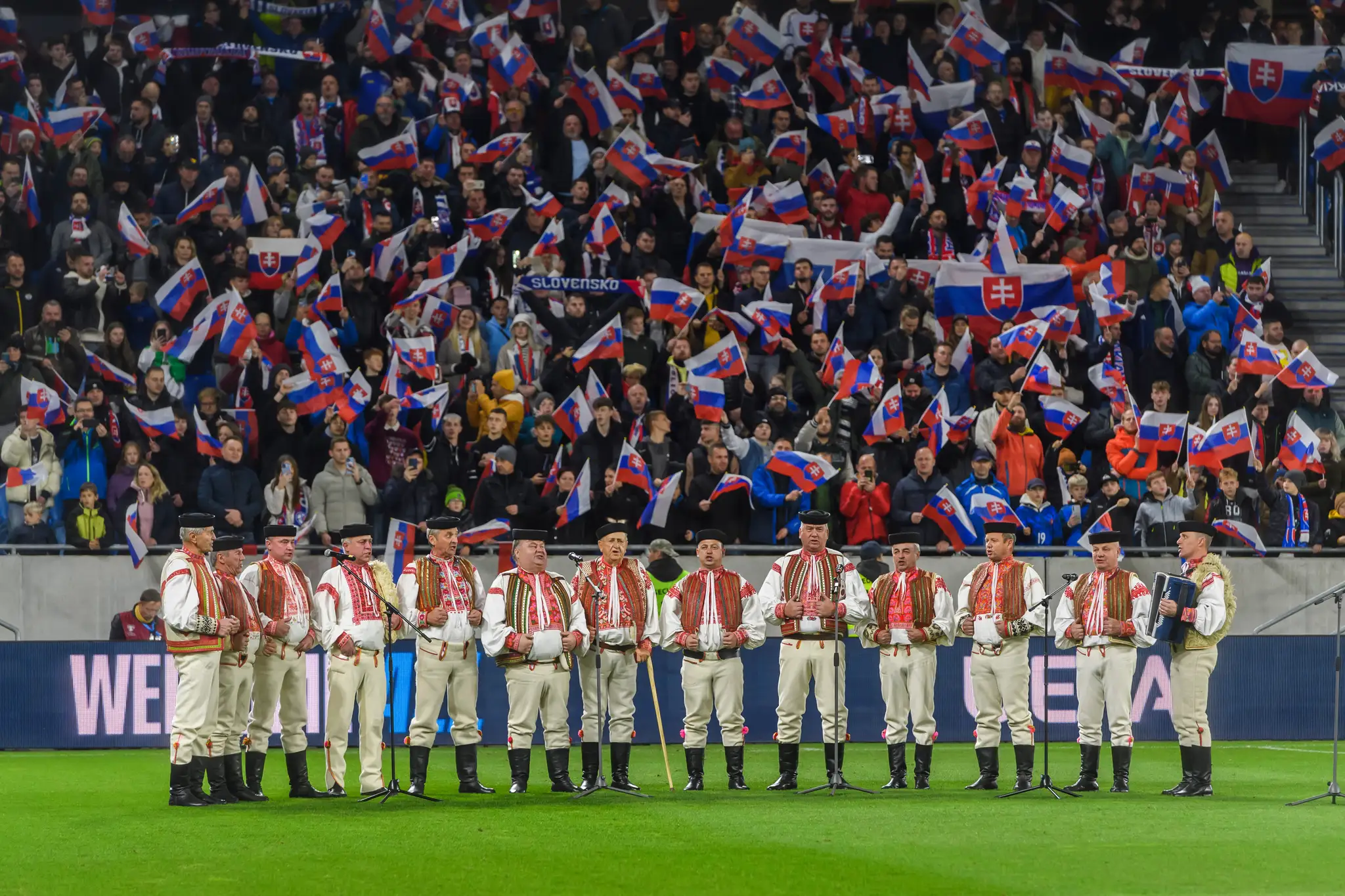 Folklórni hudobníci spievajú hymnu pred zápasom kvalifikácie ME 2024 Slovensko - Island.