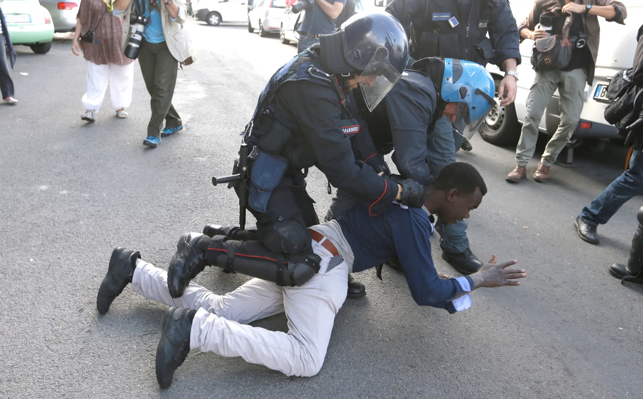 Policajti pri zaisťovaní jedného z migrantov