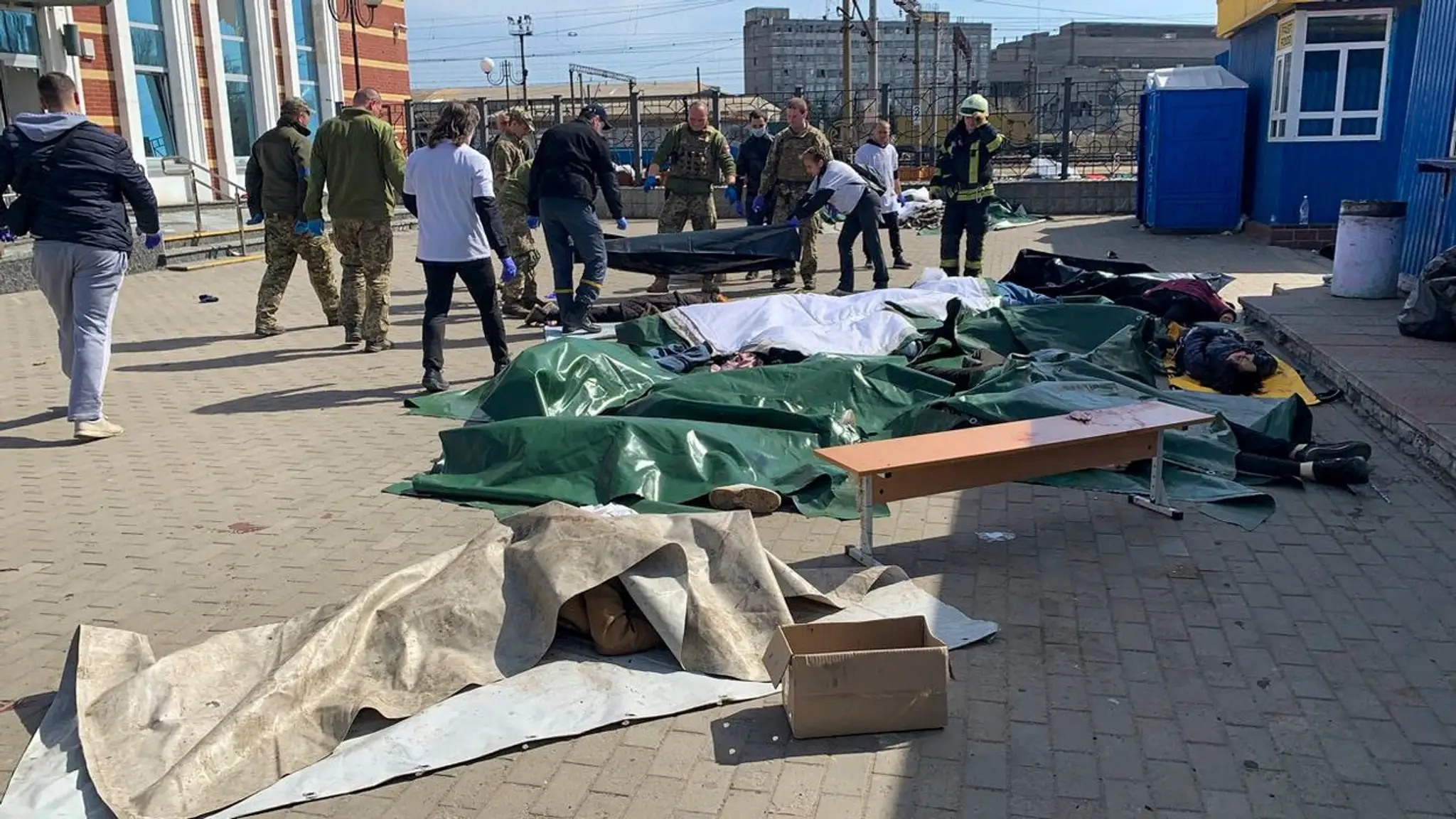 Ukrajinskí vojaci zhromažďujú telá obetí po ruskom raketovom útoku.