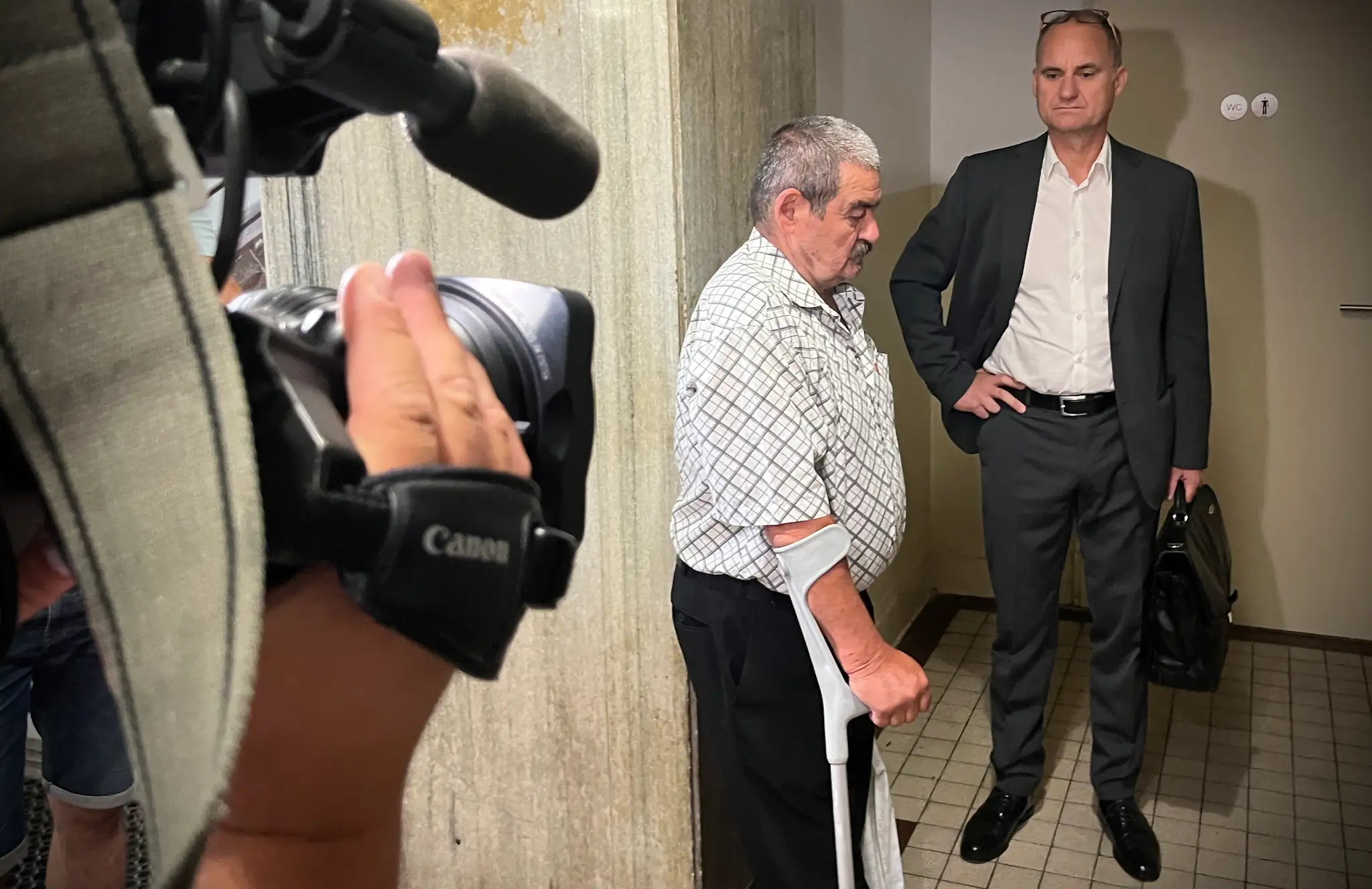 Dôchodca stojí v budove súdu.