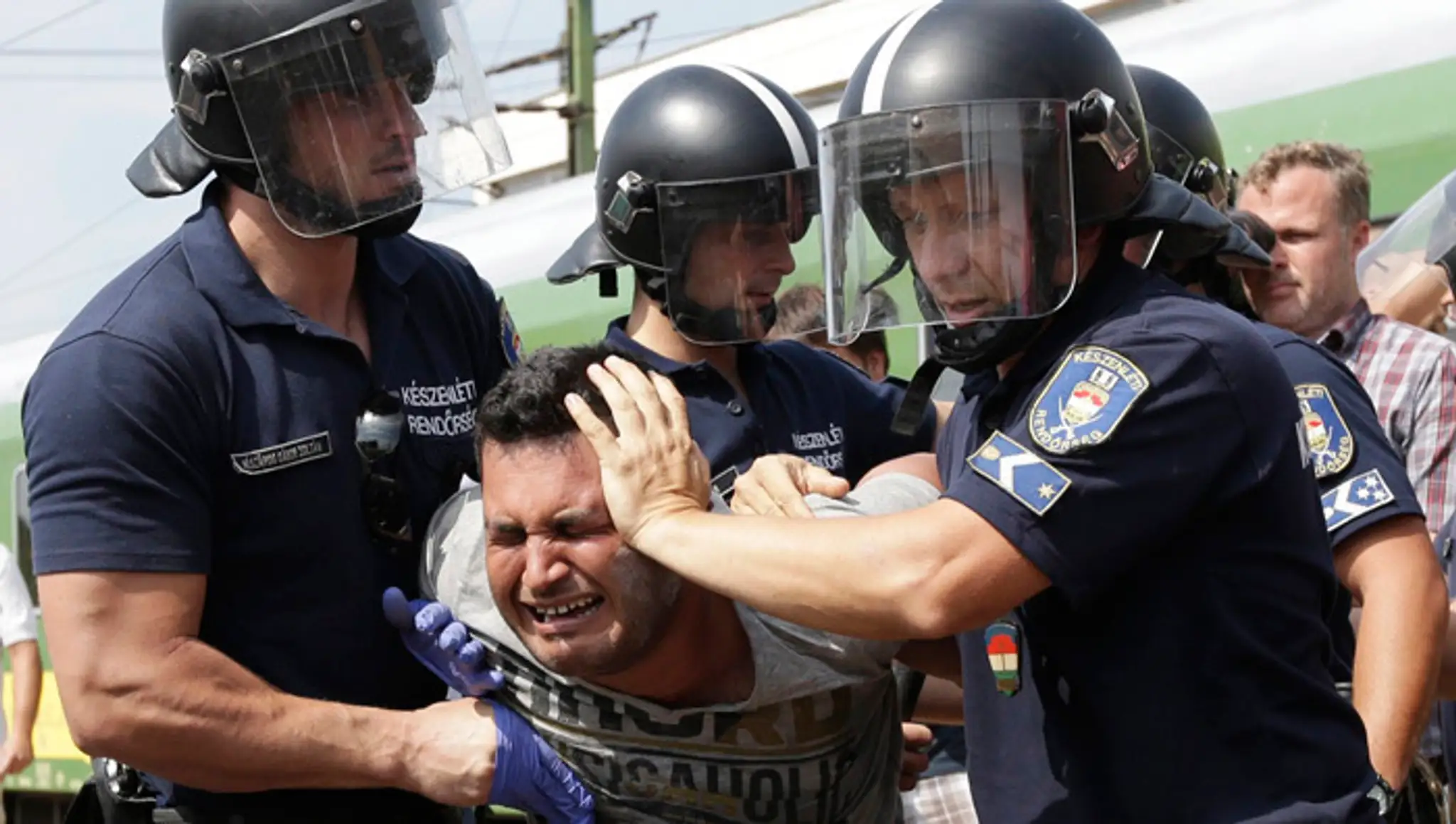 Na snímke policajti zatýkajú migranta, ktorý pricestoval vlakom z Budapešti na železničnej stanici v maďarskom meste Bicske.