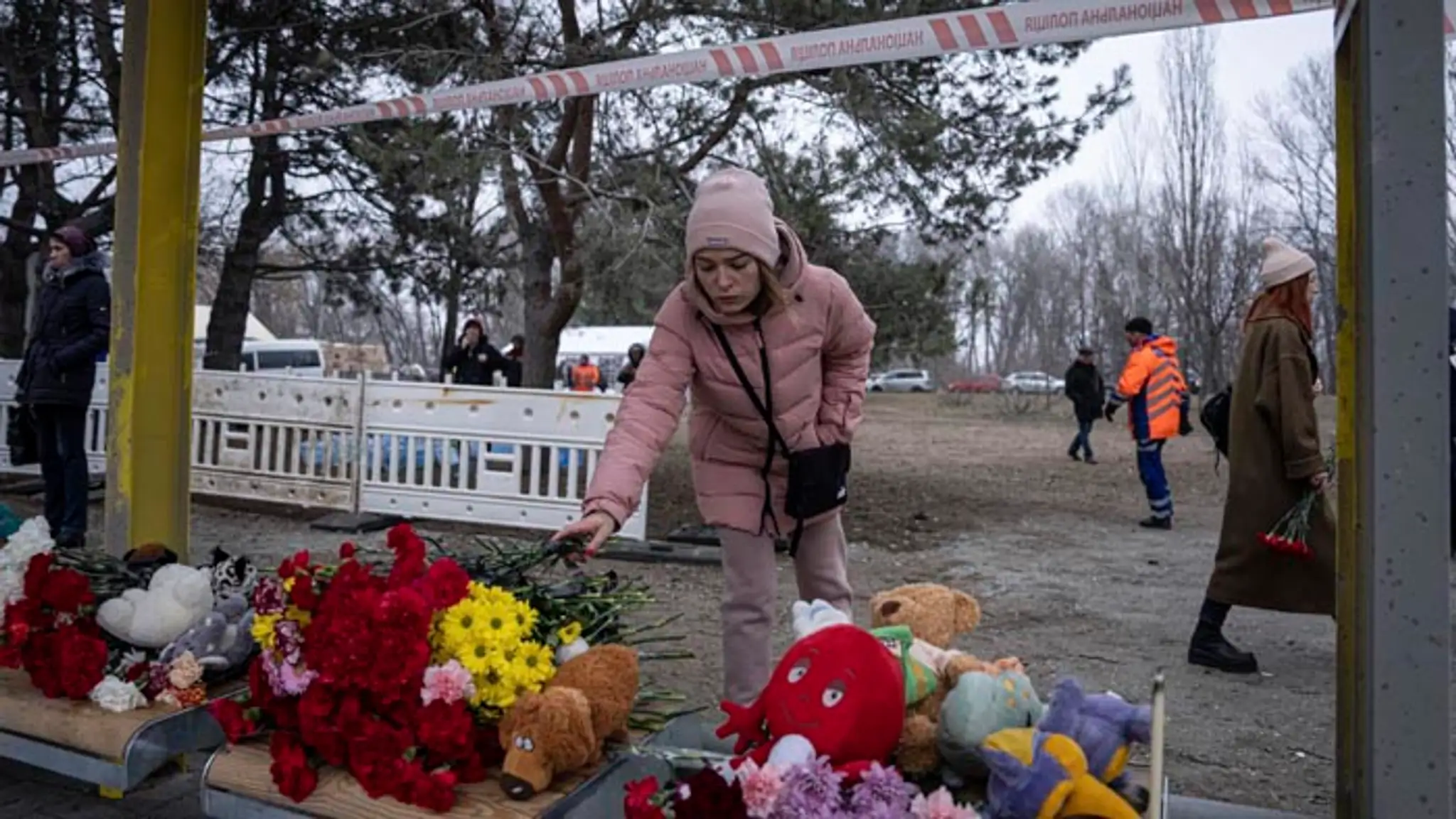 Žena kladie kvety na pamiatku ľudí, ktorí zahynuli pri ruskom raketovom útoku v Dnipre.