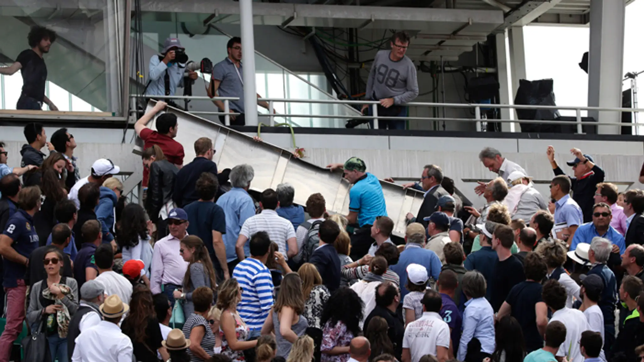 Ľudia odnášajú časť panelu, ktorý spadol na stánok na centrálnom kurte počas štvrťfinále Roland Garros.
