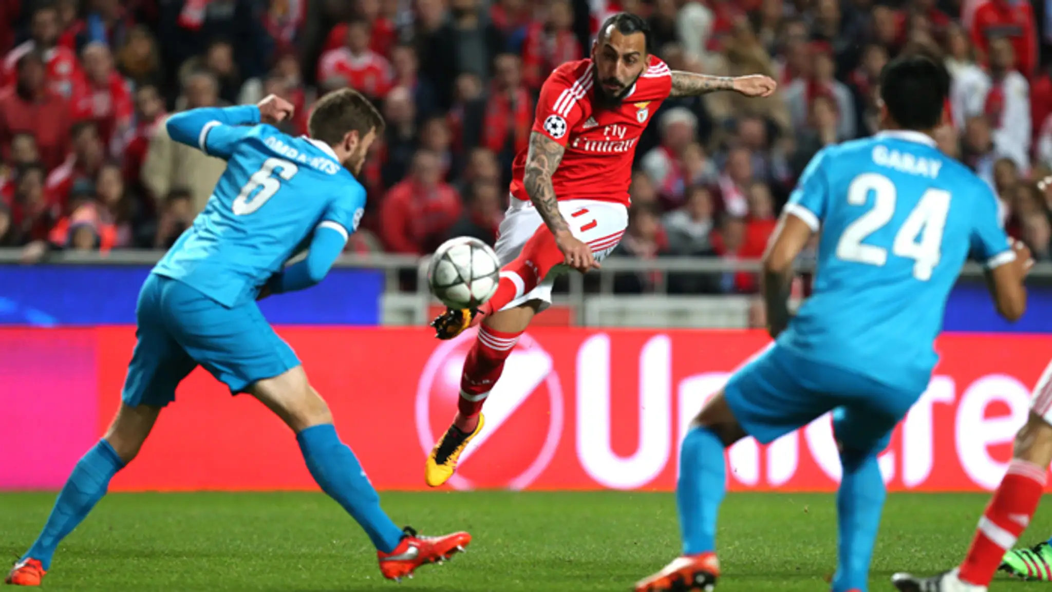 Kostas Mitroglou (Benfica) strieľa na bránu medzi Nicolasom Lombaertsom(vľavo) a Ezequiel Garay (obaja Zenit Petrohrad).