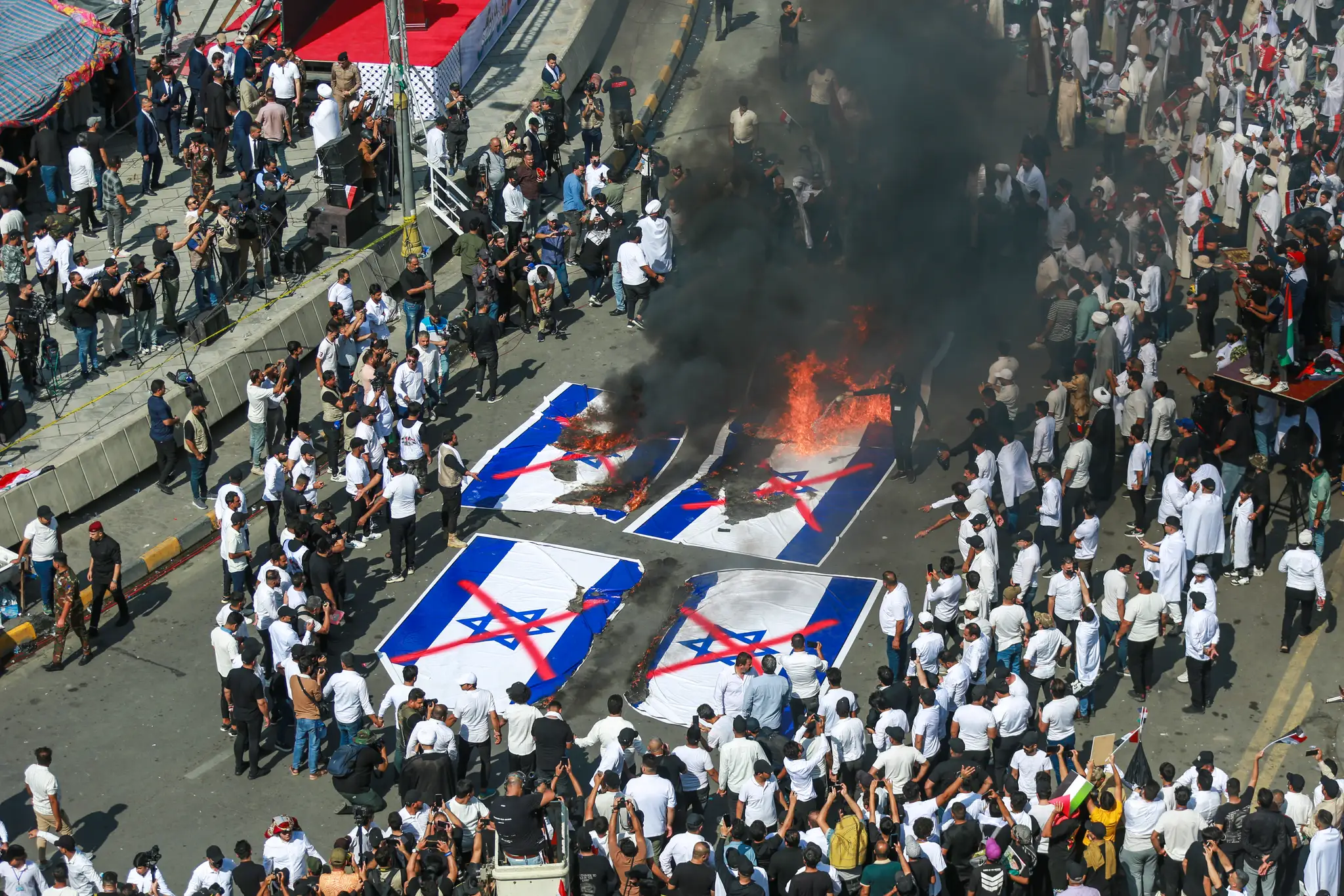 Na snímke Iračania pália izraelské vlajky počas masového zhromaždenia, na ktorom podporili Palestínčanov.