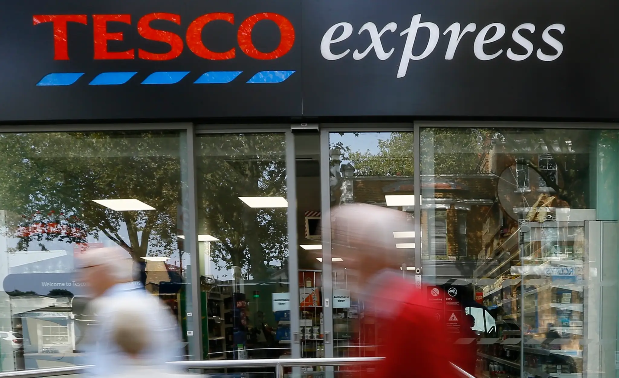 Ľudia prechádzajú okolo obchodu Tesco express.