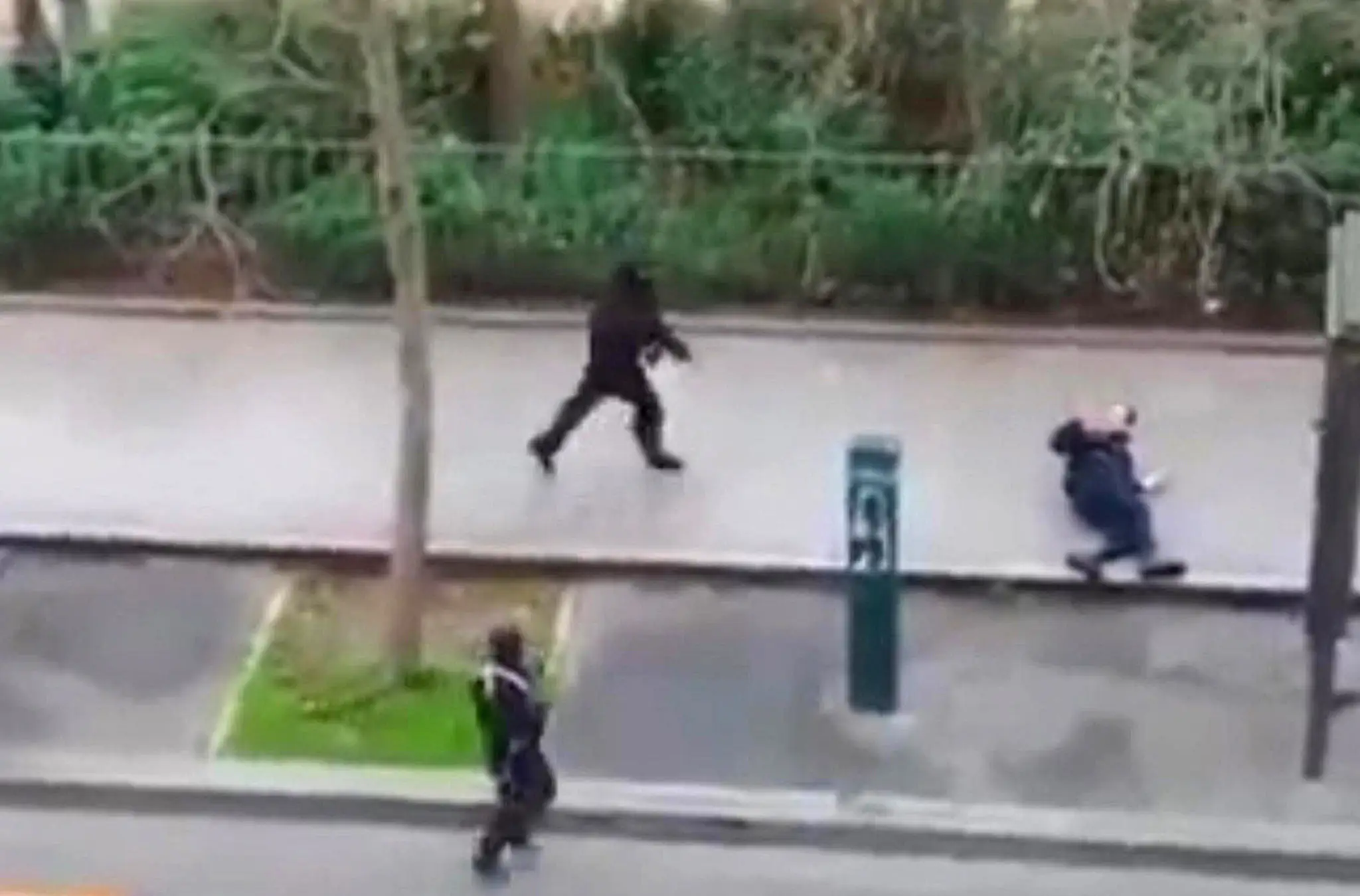 Na snímke, ktorá pochádza z videozáznamu parížskeho obyvateľa dvaja maskovaní útočníci strieľajú na človeka na ulici počas útoku