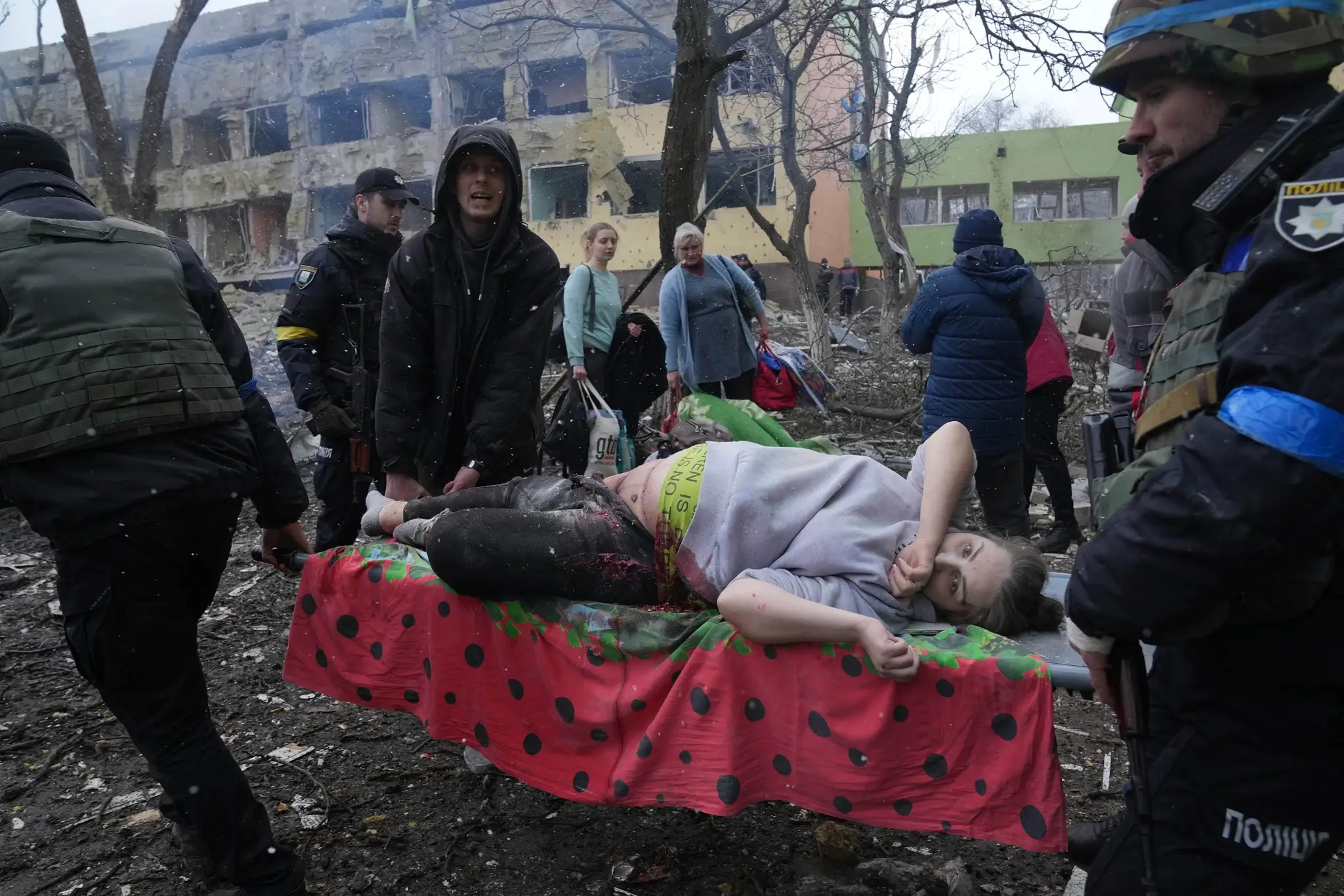 Záchranári a zdravotníci ratujú tehotnú zranenú ženu zo zbombardovanej pôrodnice v Mariupole.