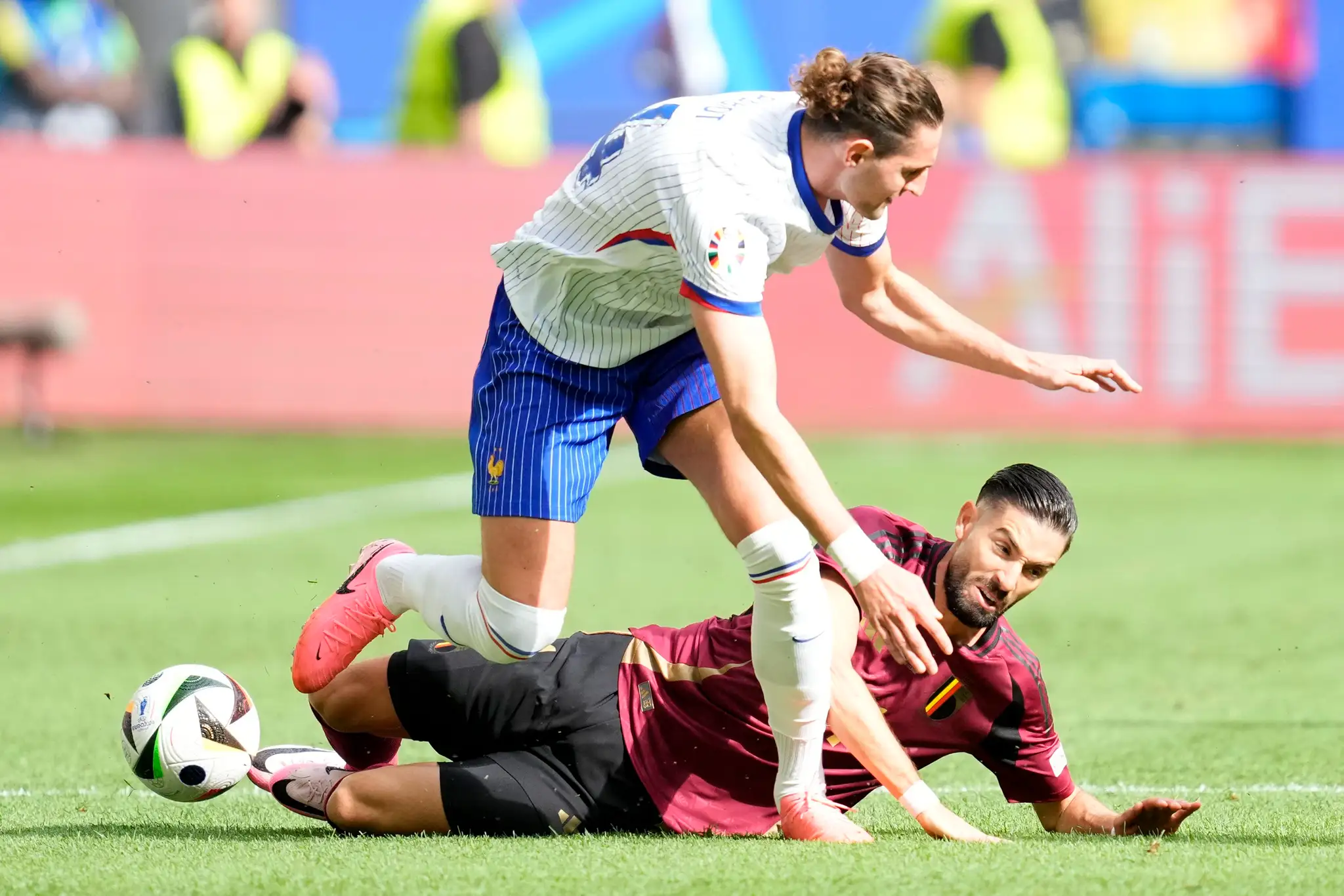Dole Belgičan Dodi Lukebakio v súboji s Francúzom Adrienom Rabiotom v osemfinále ME 2024.