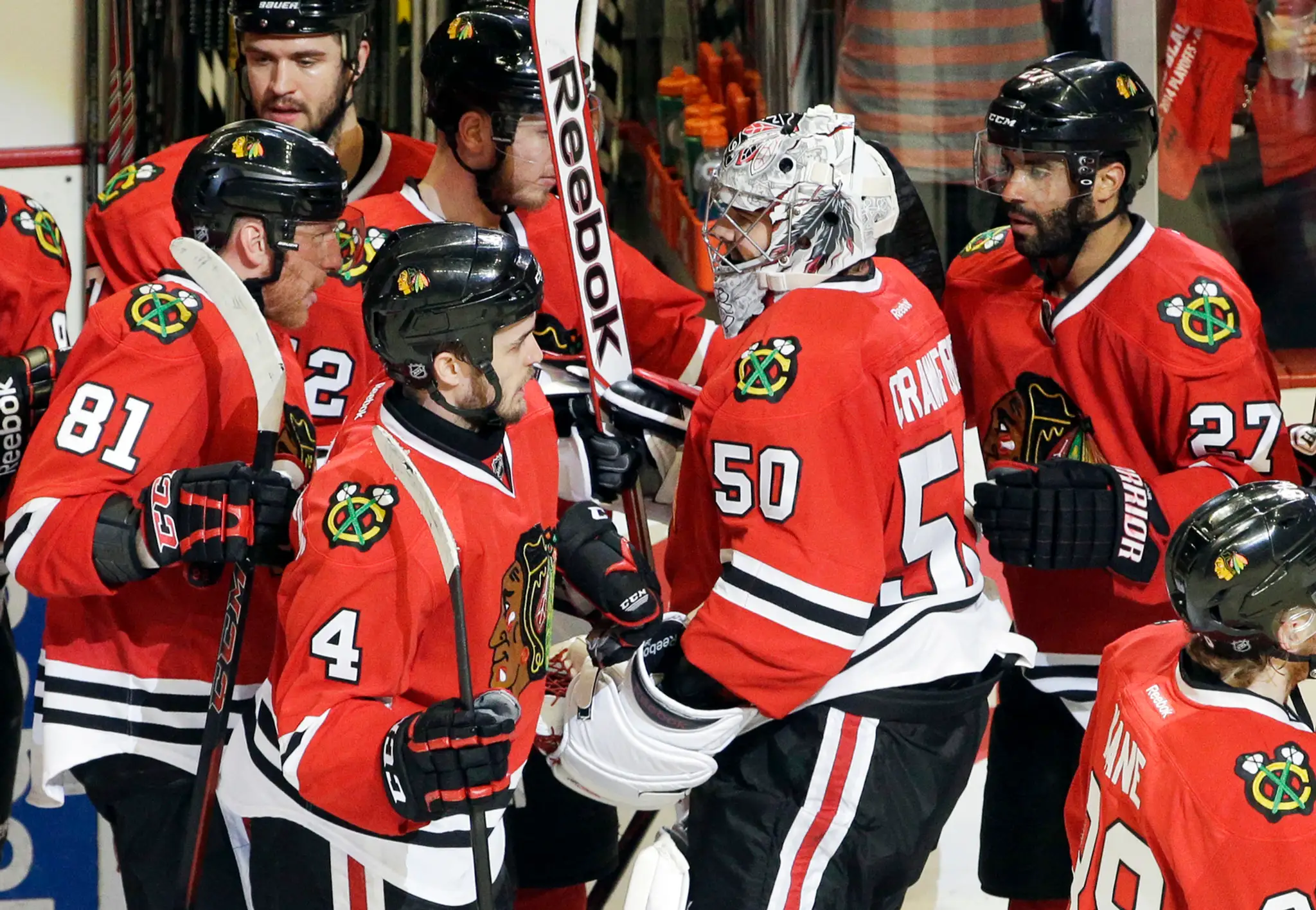 Brankár Chicaga Blackhawks Corey Crawford (50) sa raduje so spoluhráčmi z víťazstva 2:1 nad Minnesotou Wild, vľavo Slovák Marián