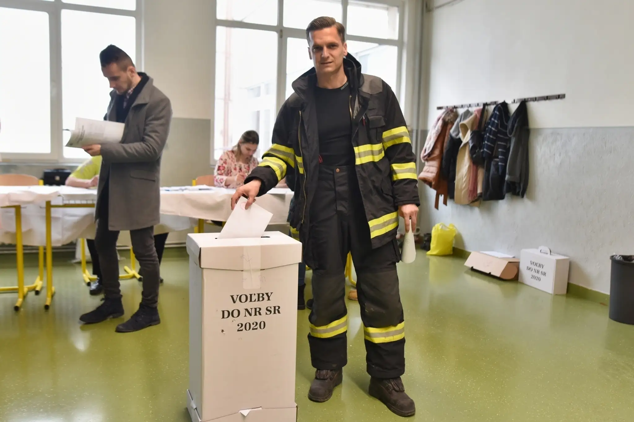 Postihnutý volič na vozíku vhadzuje hlasovací lístok do prenosnej volebnej schránky.