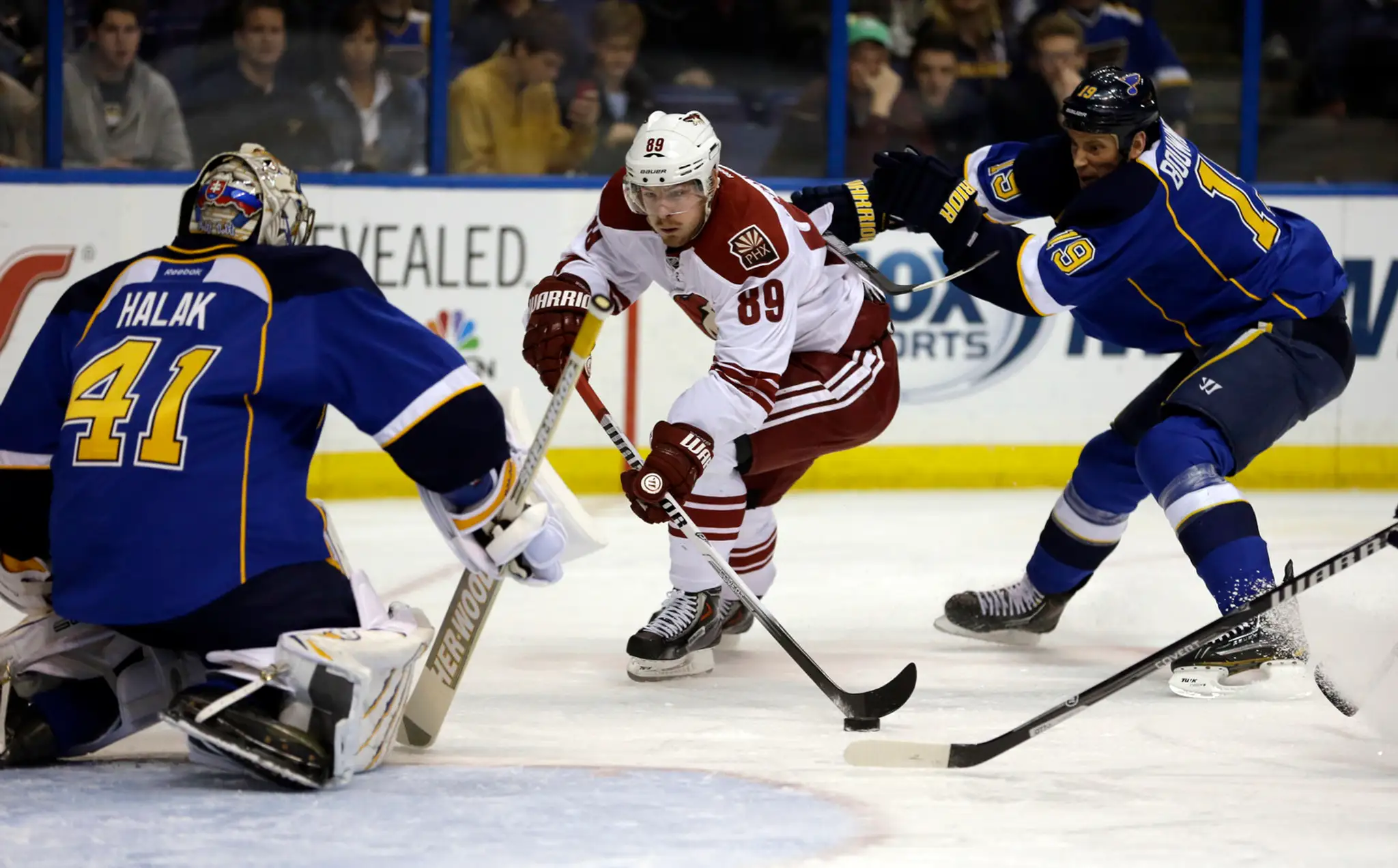 Hokejista Phoenixu Coyotes Mikkel Boedker (uprostred) z Dánska, brankár St. Louis Blues Slovák Jaroslav Halák (vľavo) a jeho spo