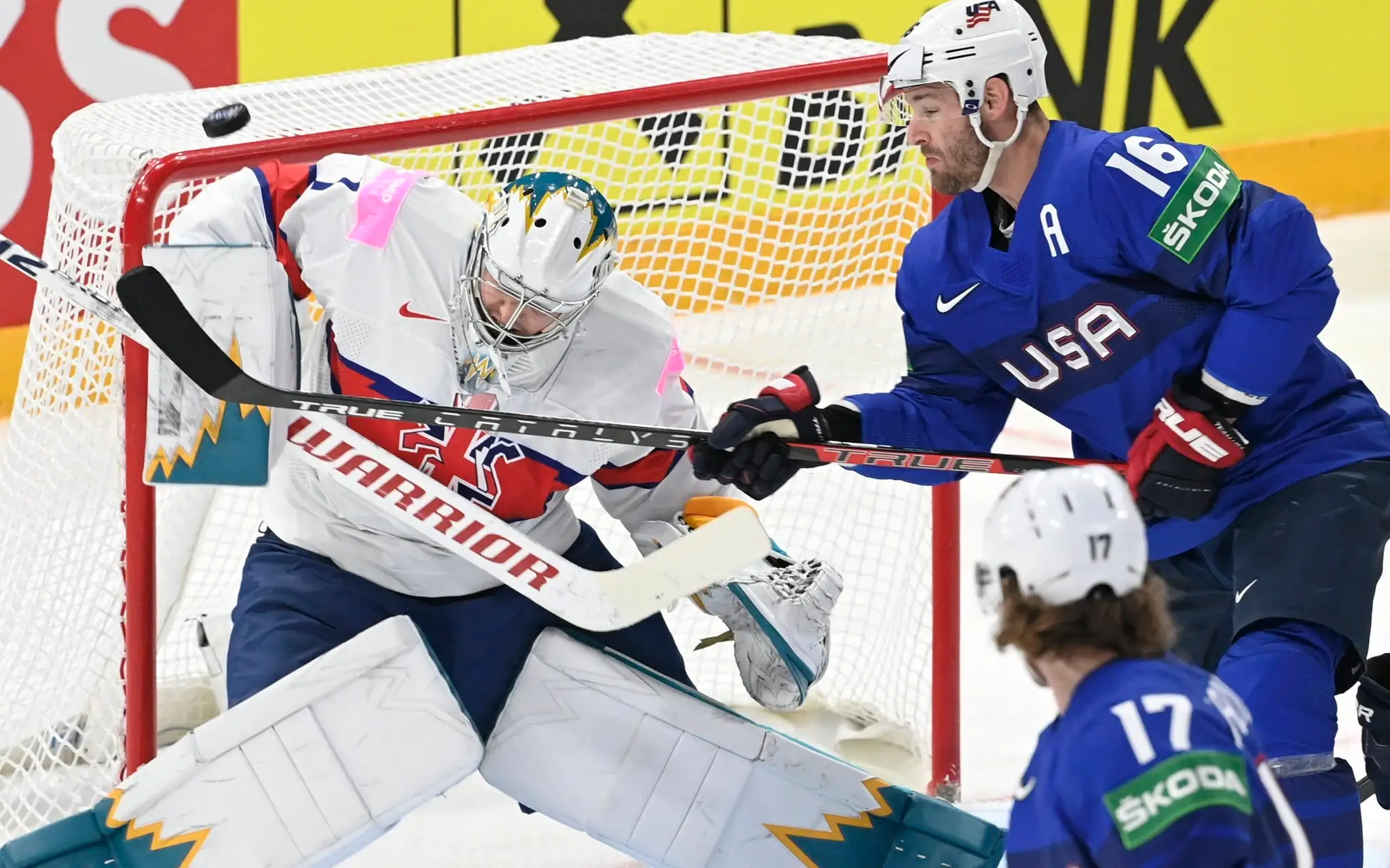 Na snímke zľava  britský brankár Jackson Whistle, americký hráč Austin Watson a dole jeho spoluhráč Adam Gaudette.