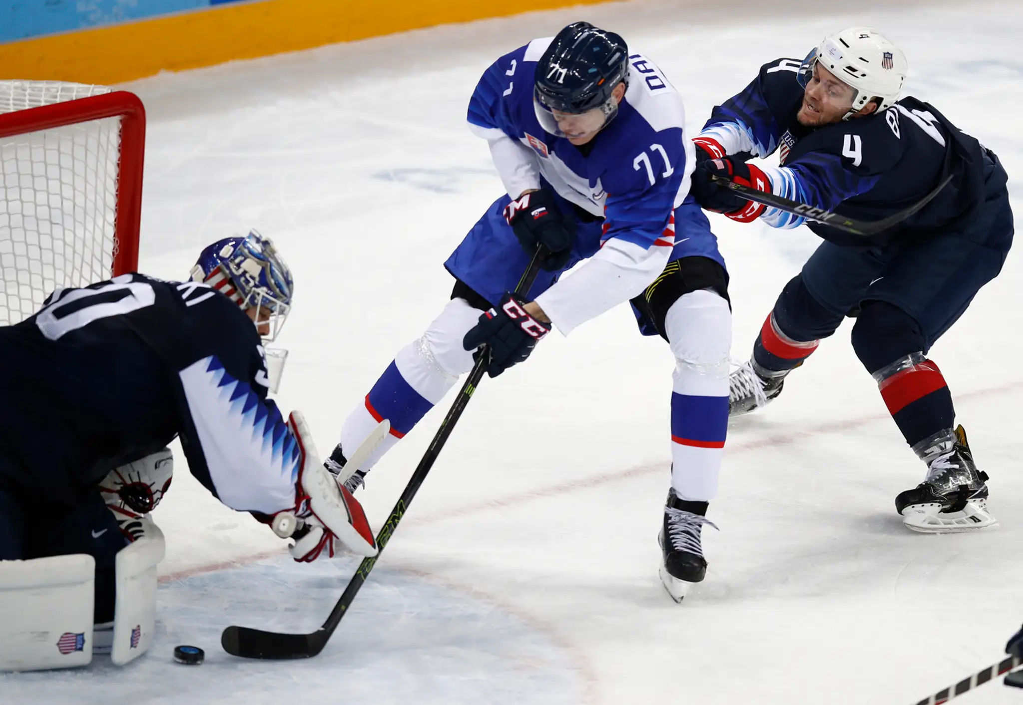 Slovenský obranca Marek Ďaloga sa počas osemfinále ZOH 2018 tlačí pred bránku USA, v ktorej stojí Ryan Zapolski.