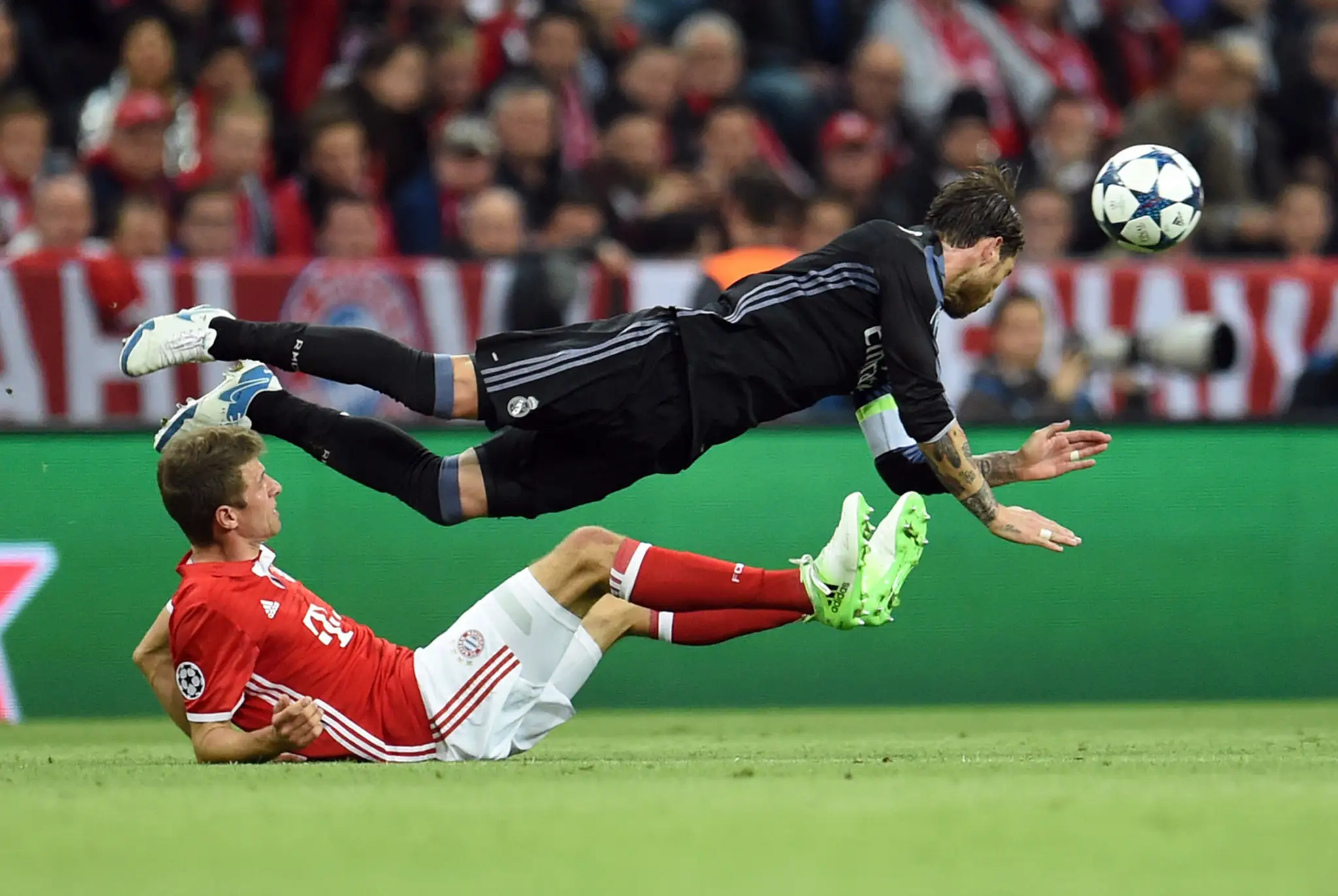 Thomas Müller (dole) z Bayernu v súboji o loptu s kapitánom Realu Sergiom Ramosom vo štvrťfinále LM.