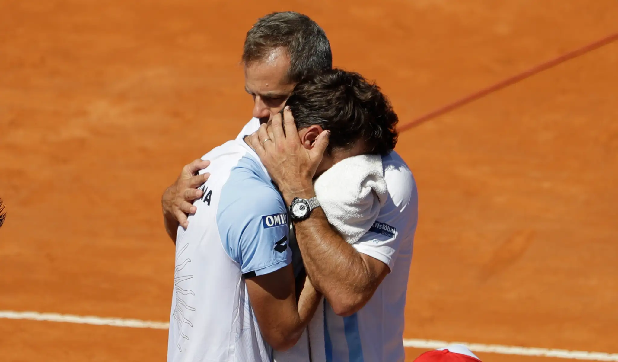 Kouč Argentíny Daniel Orsanic (vpravo) utešuje svojho zverenca Guida Pella po prehre s Talianom Fogninim v zápase Davis Cupu.