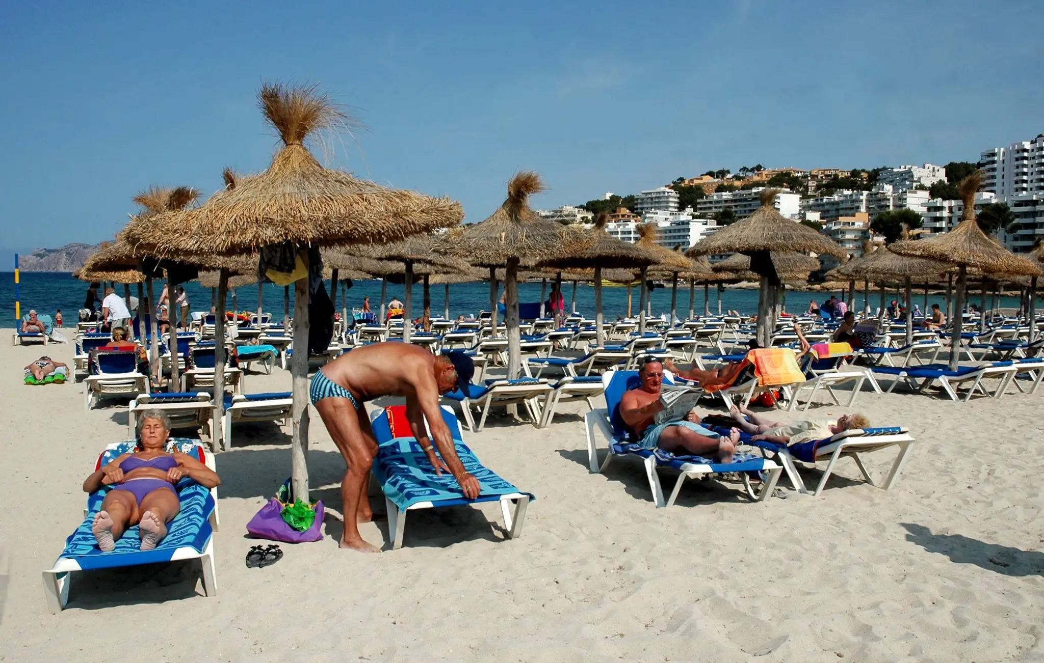 Turisti odpočívajú na piesočnatej pláži v Palme, hlavnom meste španielskeho ostrova Malorka.