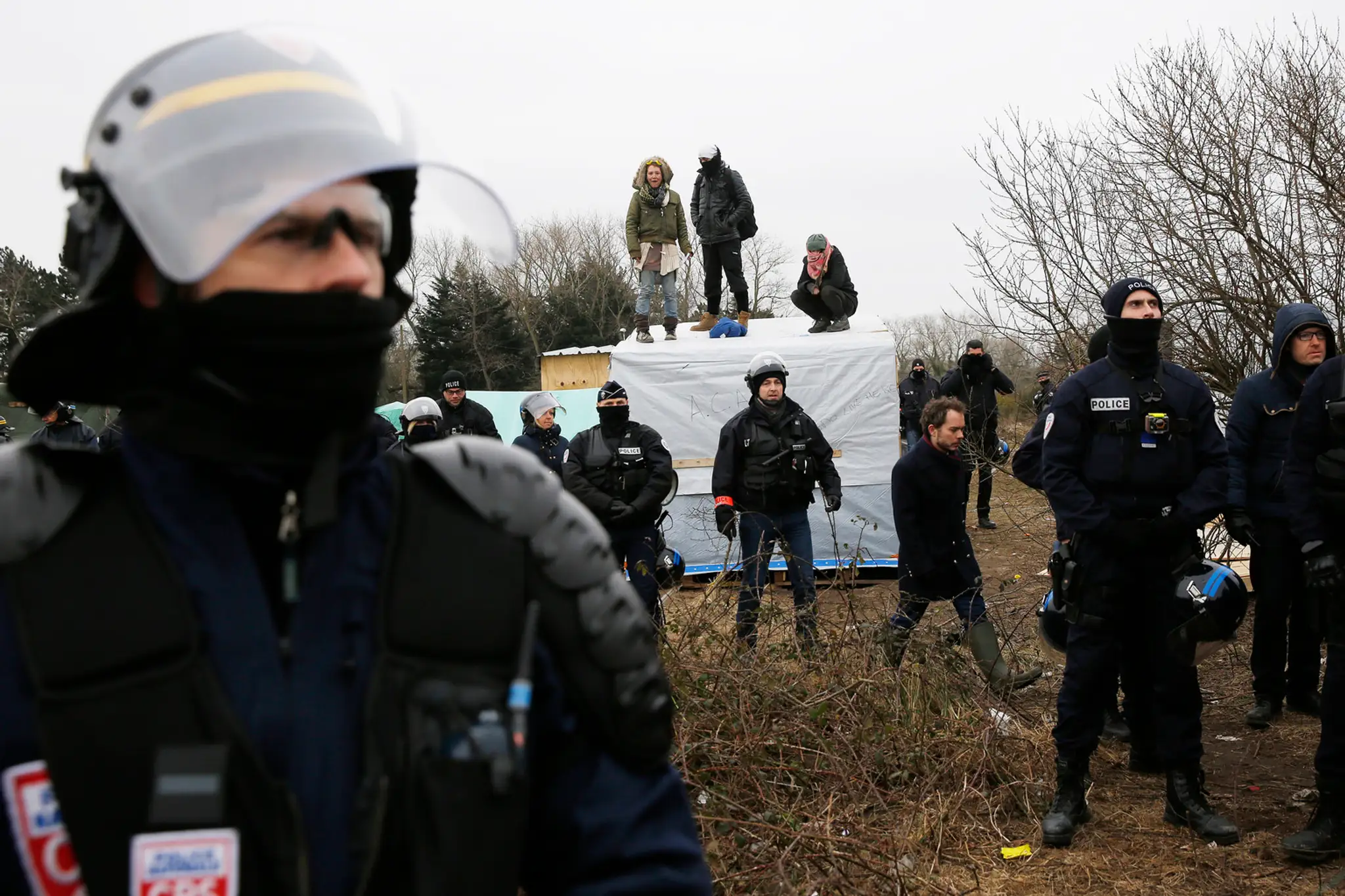 Migranti v tábore pri Calais protestujú na strechách búd.