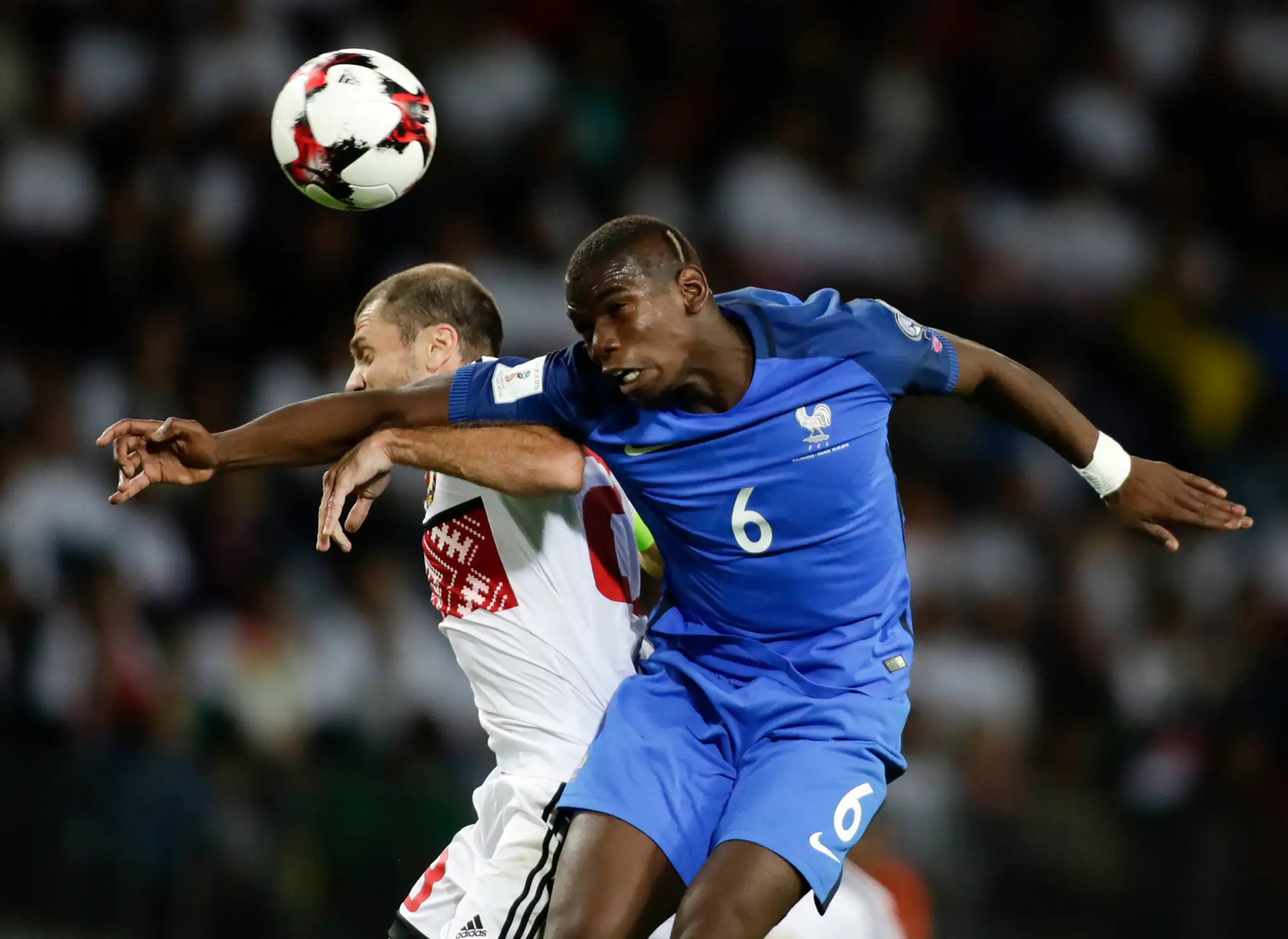 Megahviezda Francúzska Paul Pogba (v modrom) hlavičkuje pred bieloruským Ivanom Majevskim v kvalifikácii MS 2018.