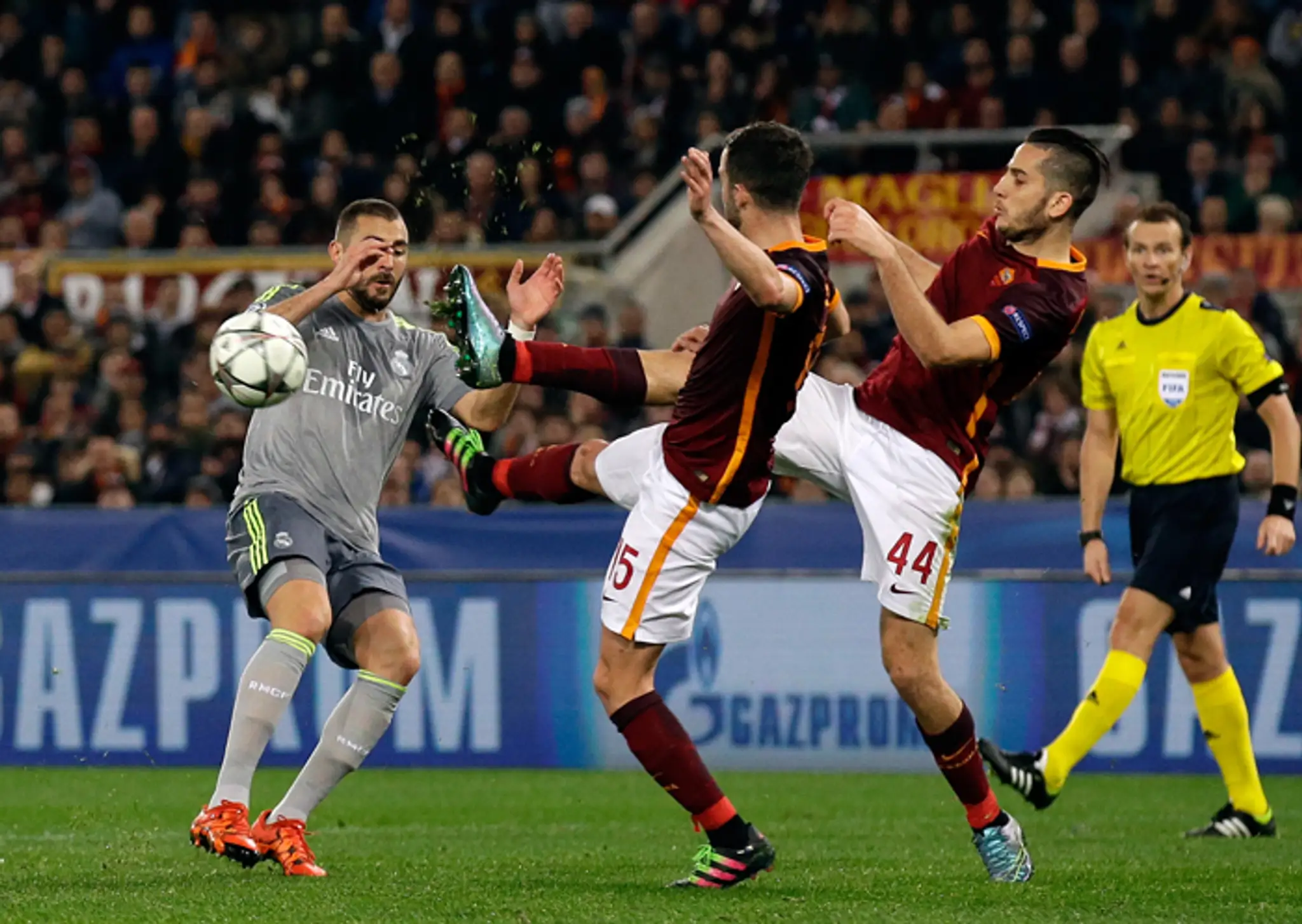 Hráči AS Rím Miralem Pjanič (v strede) a Konstantinos Manolas (vpravo) v súboji s Karimom Benzemom (Real) v osemfinále LM.