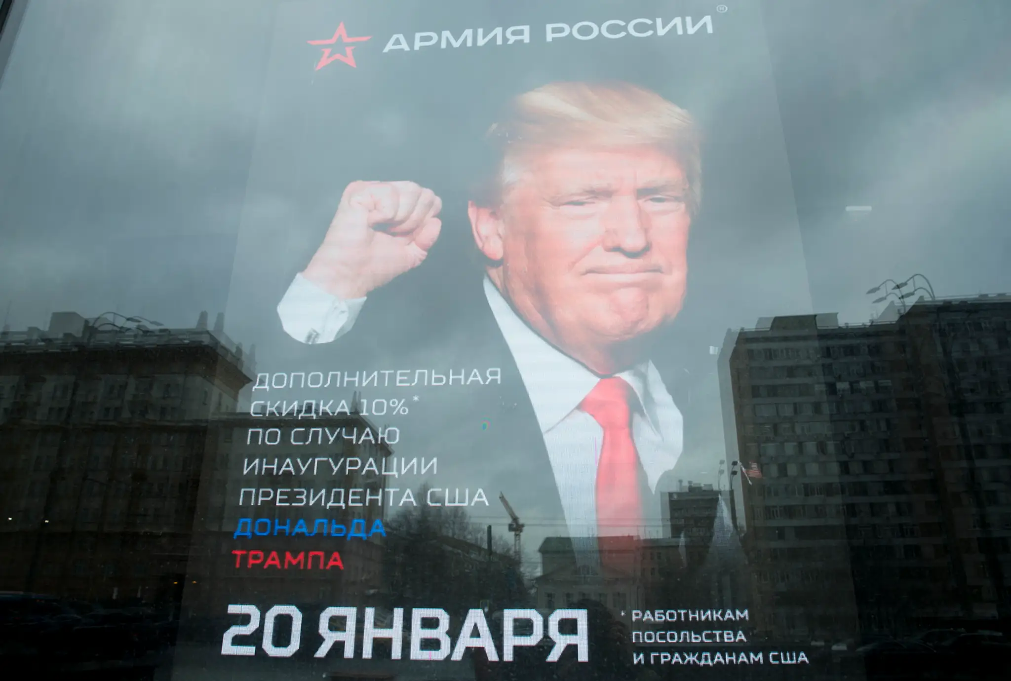 Budova veľvyslanectva USA sa odráža na okne obchodu s plagátom Donalda Trumpa v Moskve.