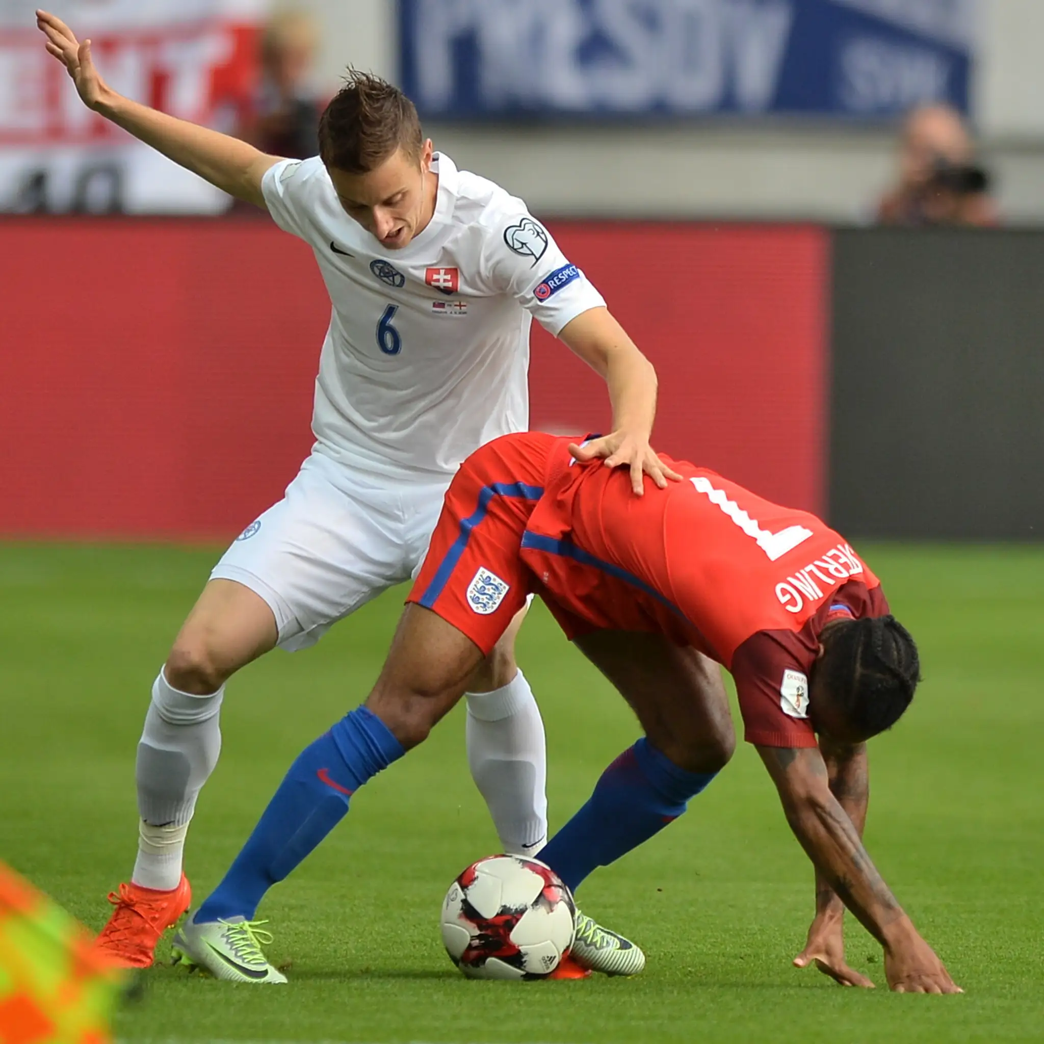 Ján Greguš (v bielom) a vpravo Angličan Raheem Sterling v súboji o loptu v kvalifikačnom dueli na MS 2018.