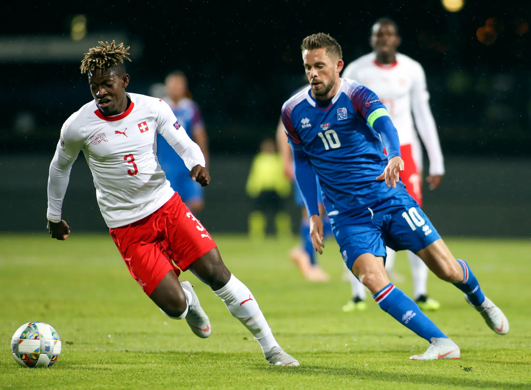 Švajčiar Francois Moubandje (vľavo) a Gylfi Sigurdsson z Islandu bojujú o loptu v zápase Ligy národov.