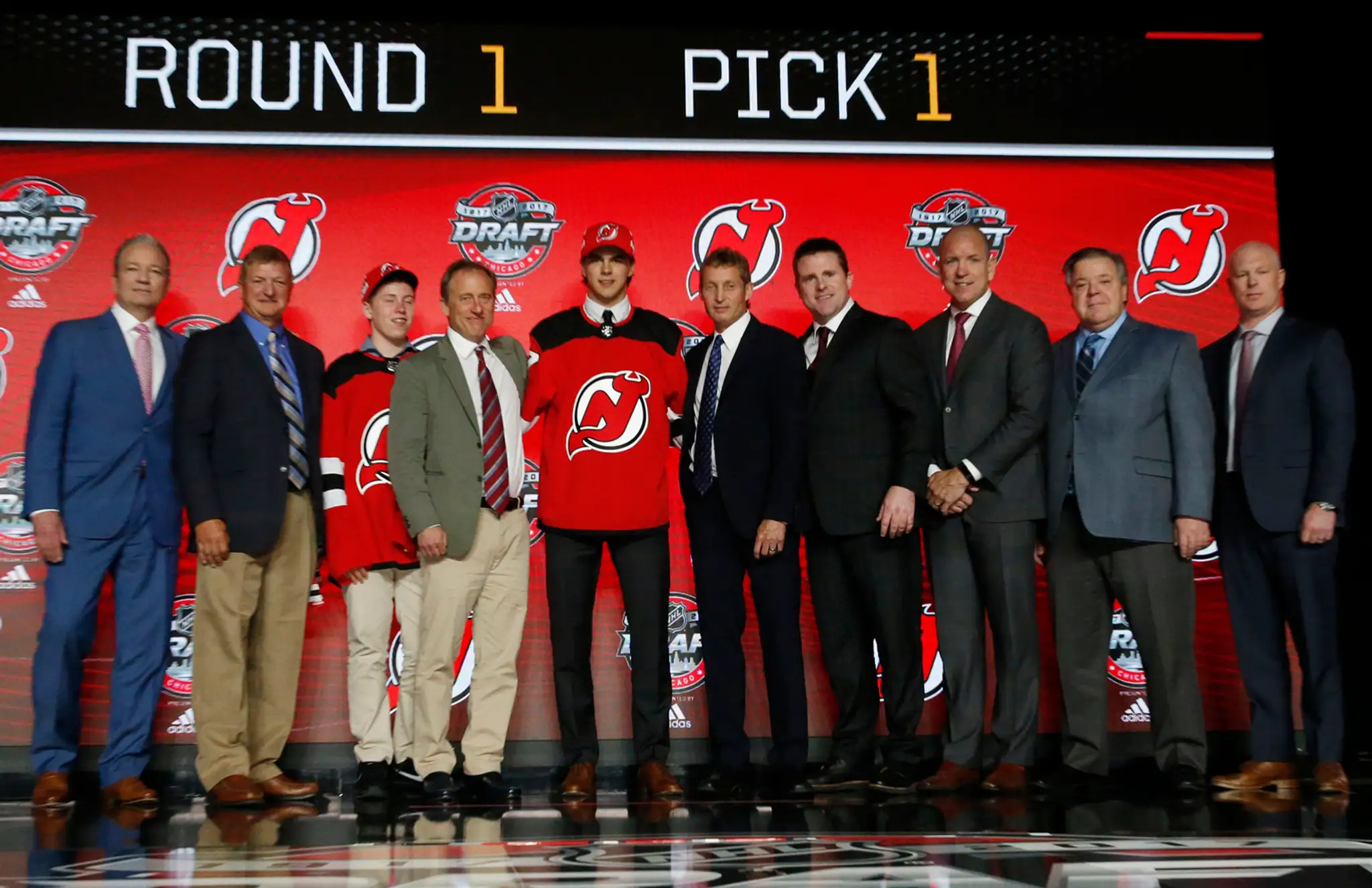 Nico Hischier (uprostred) pózuje v drese hokejového tímu New Jersey Devils, ktorý si ho vybral ako jednotku draftu 2017.