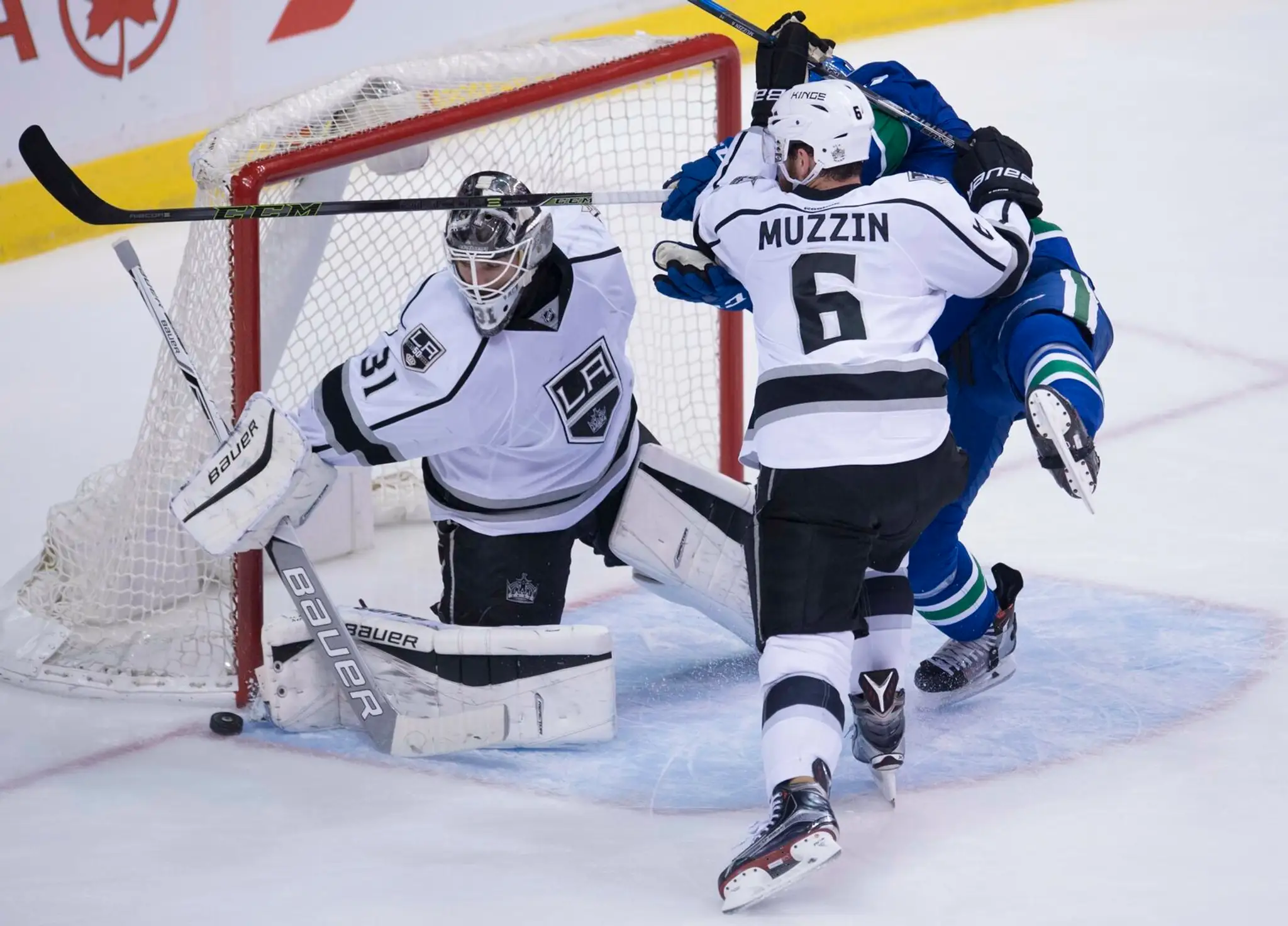 Obranca LA Kings Jake Muzzin sa snaží odstaviť dotiersajúceho Jacka Skilleho pred bránkou Petra Budaja.
