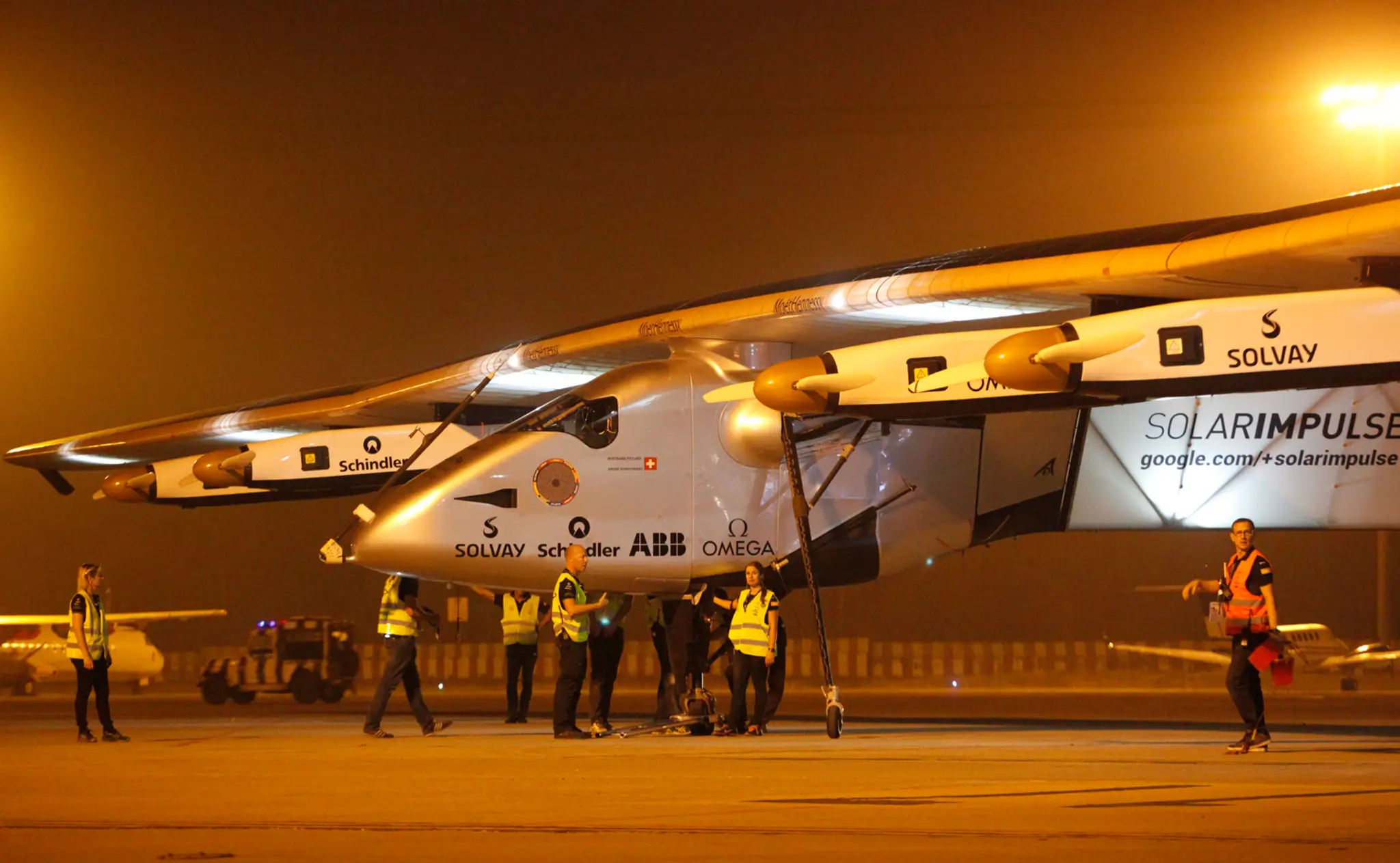 Na snímke členovia tímu tlačia švajčiarske experimentálne lietadlo Solar Impulse-2.