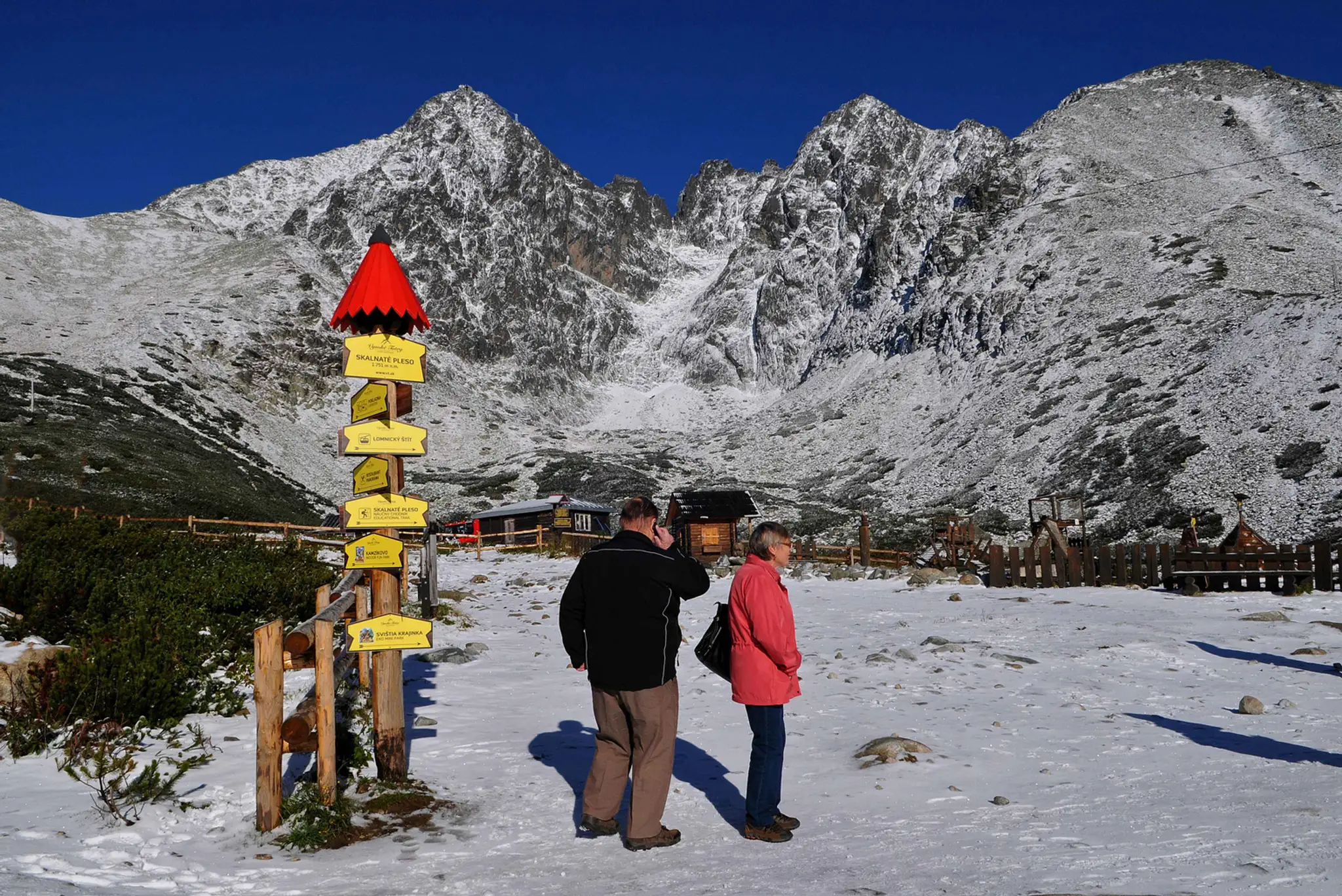 Turisti na zasneženom Skalnatom Plese, v pozadí Lomnický štít vo Vysokých Tatrách 24. septembra