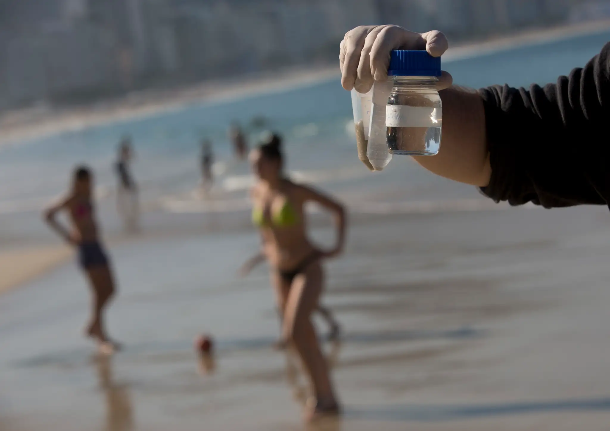 Doktorand Rodrigo Staggemeier ukazuje vzorky vody a piesku z pláže Copacabana.