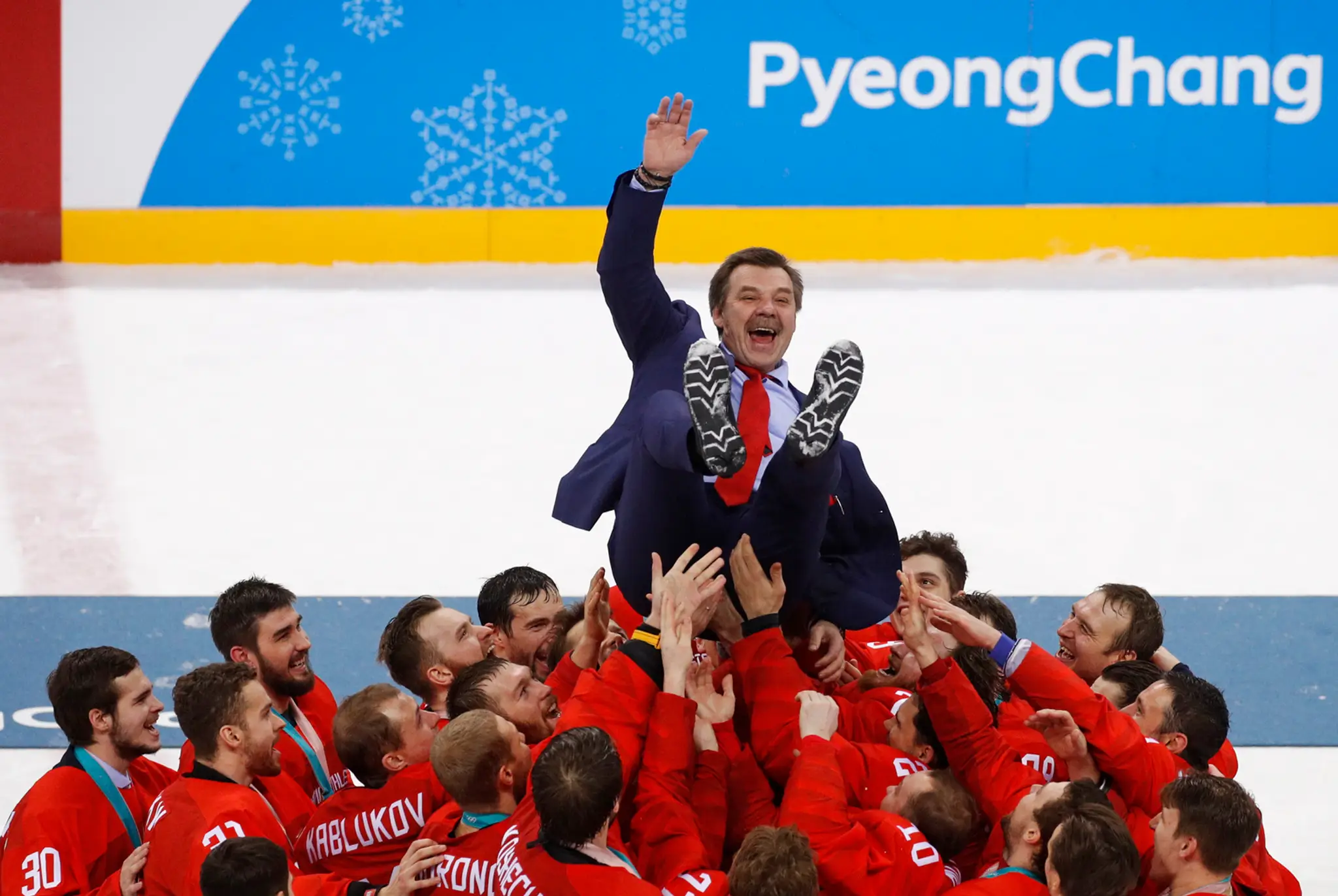 Olympijskí športovci z Ruska vyhadzujú nad hlavy svojho trénera Olega Znaroka po zisku zlatých olympijských medailí.