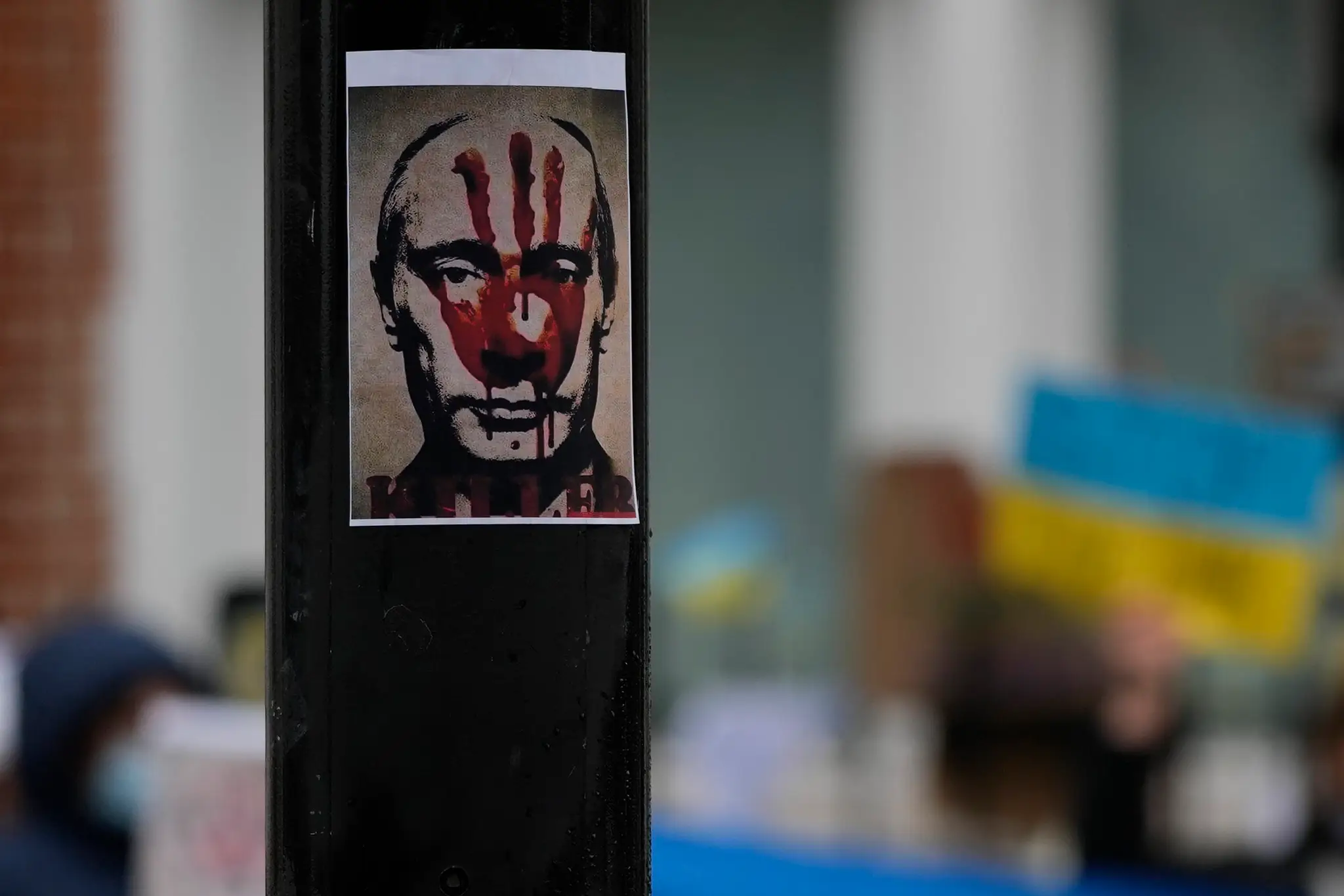 Plagát s krvavým odtlačkom dlane na tvári ruského prezidenta Vladimira Putina visí na stĺpe počas protestu proti vojne na Ukrajine