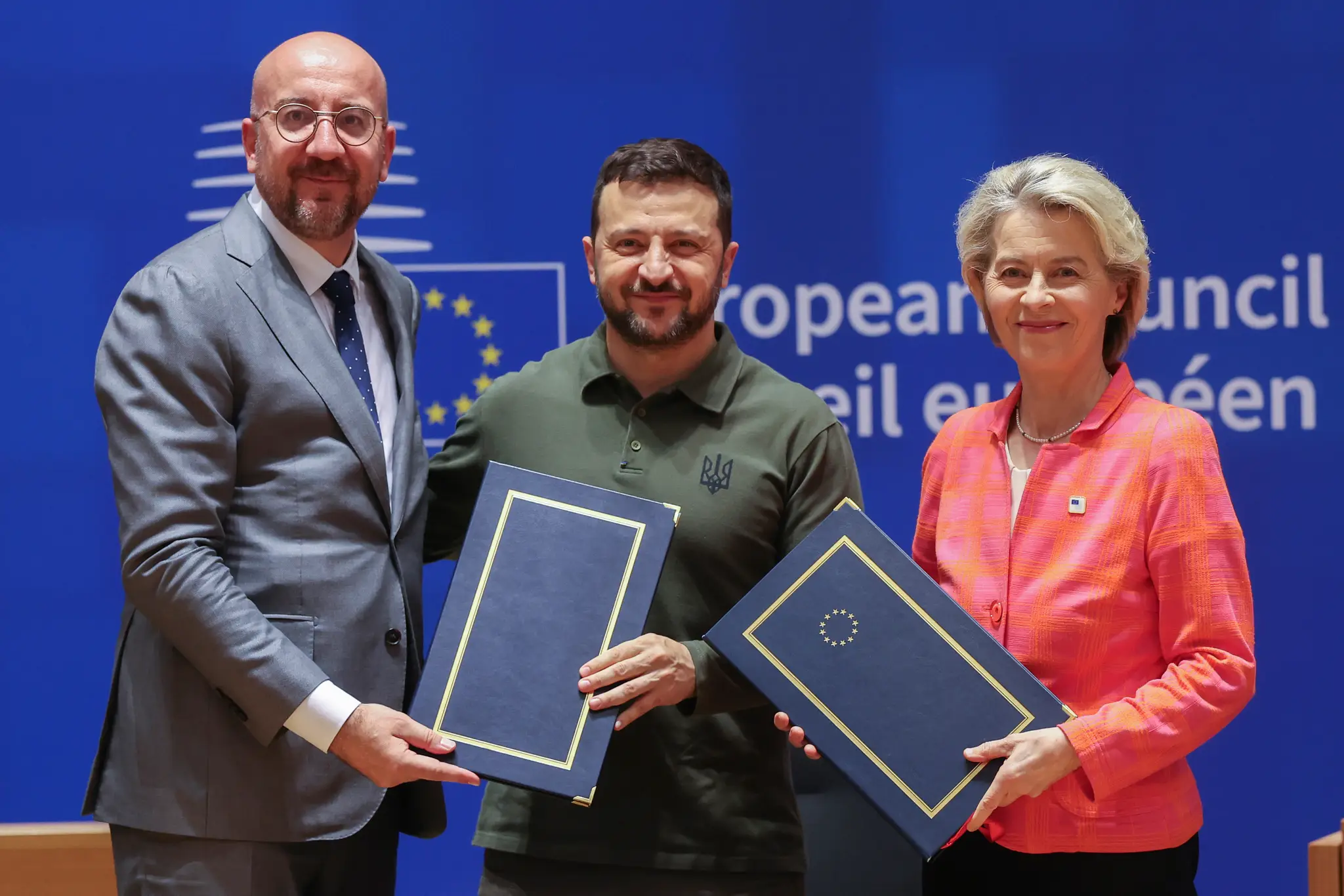 Zľava predseda Európskej rady Charles Michel, ukrajinský prezident Volodymyr Zelenskyj a predsedníčka Európskej komisie Ursula von der Leyenová pózujú po podpise bezpečnostného paktu.