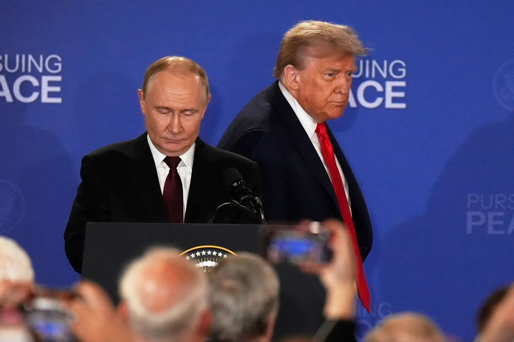 Na snímke sprava americký prezident Donald Trump a ruský prezident Vladimir Putin prichádzajú na spoločnú tlačovú konferenciu na vojenskej základni Elmendorf-Richardson.